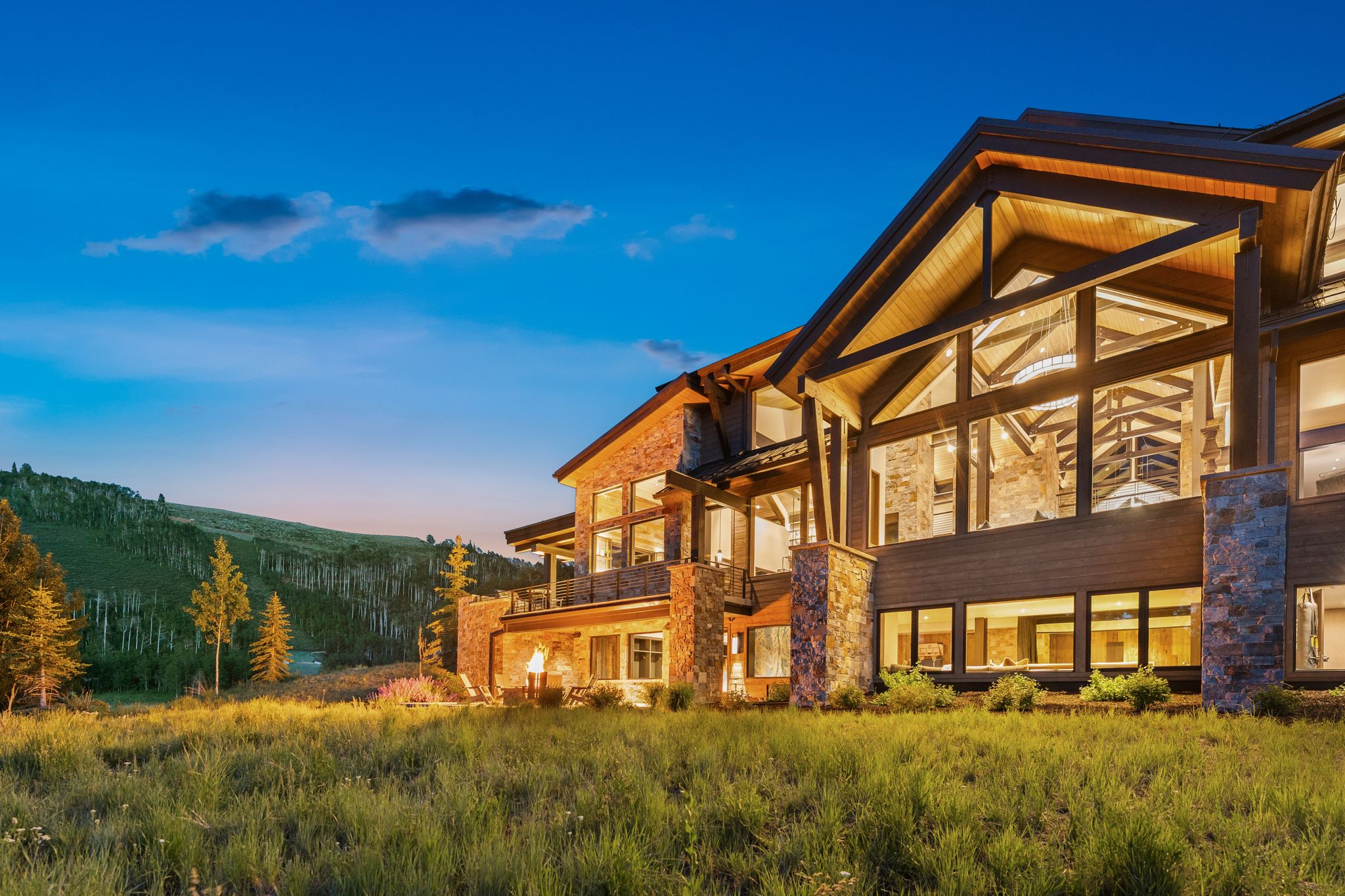 Custom-built residence featuring extensive window walls, exposed timber beams, and natural stone accents