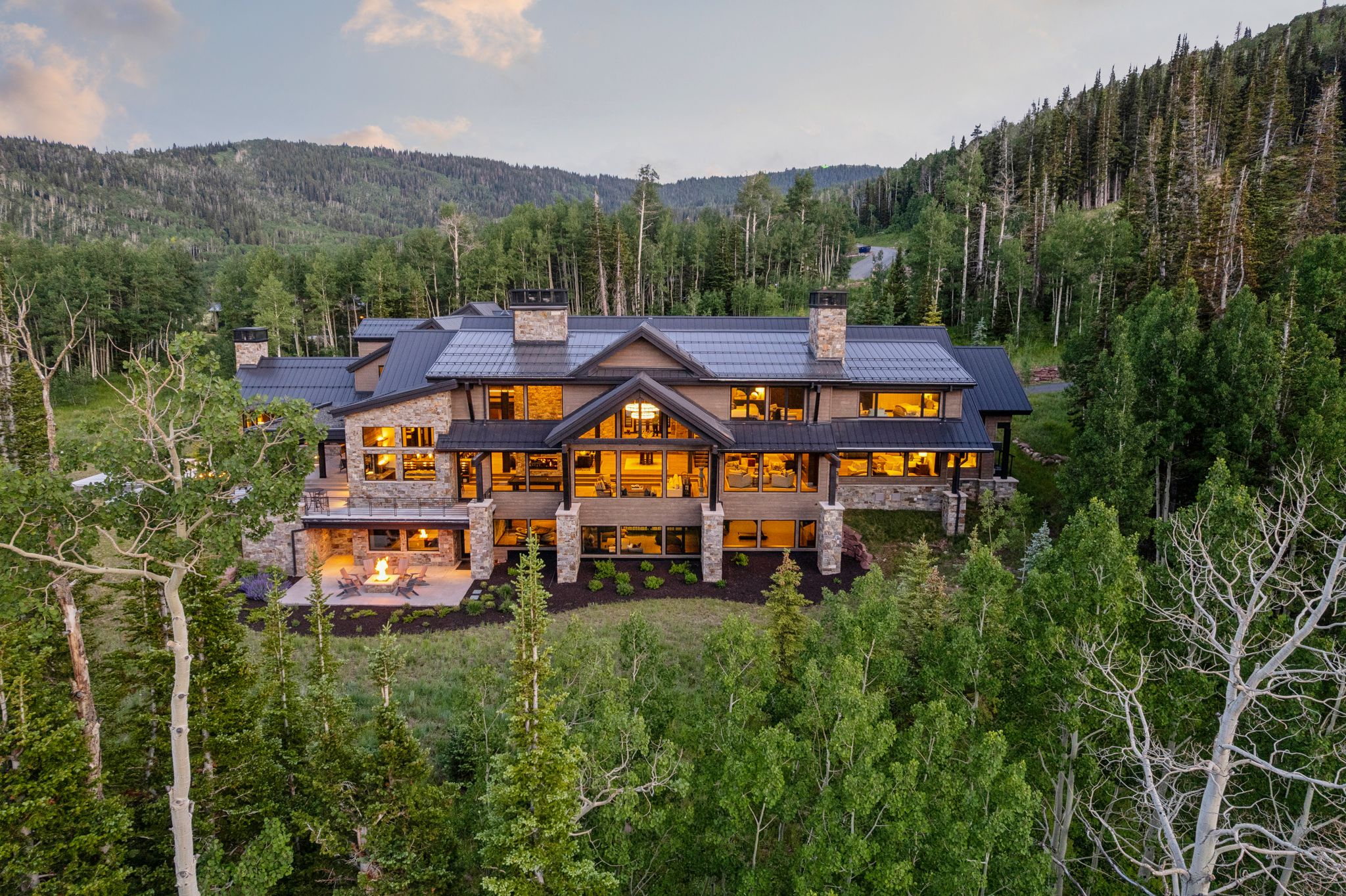 Expansive mountain-style residence featuring a stone and stucco exterior, multiple gables, and a dark metal roof