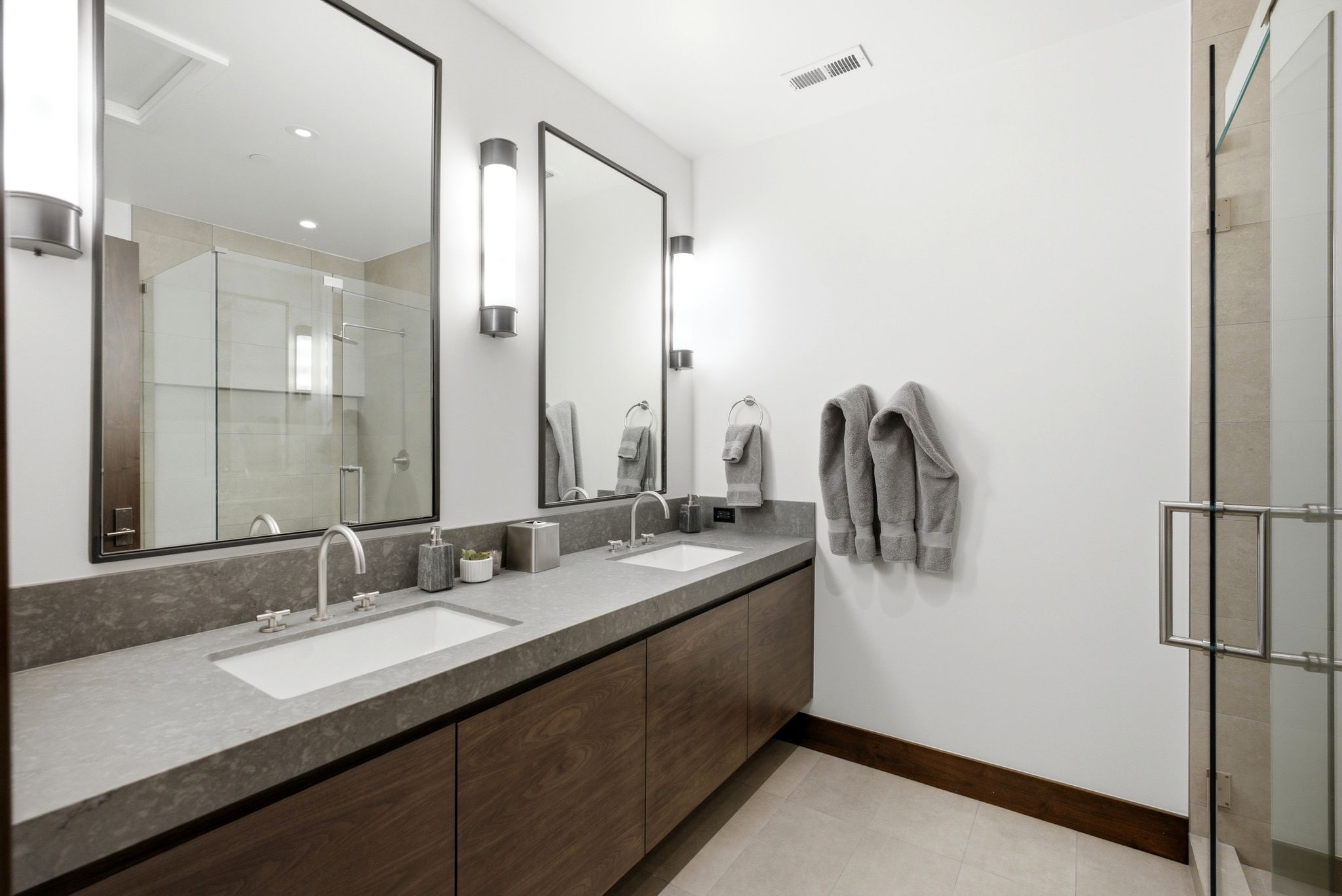 Dual floating wood-finish vanity with integrated rectangular sinks, stone countertops, and brushed nickel fixtures