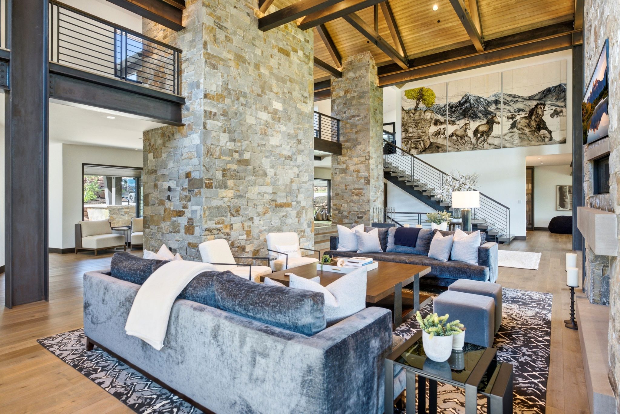 Spacious living area featuring exposed beam ceilings, light wood-finish flooring, and a stone accent wall