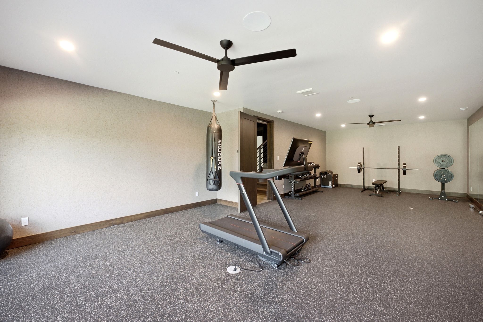 Spacious recreation room featuring recessed lighting, two ceiling fans, and durable speckled flooring