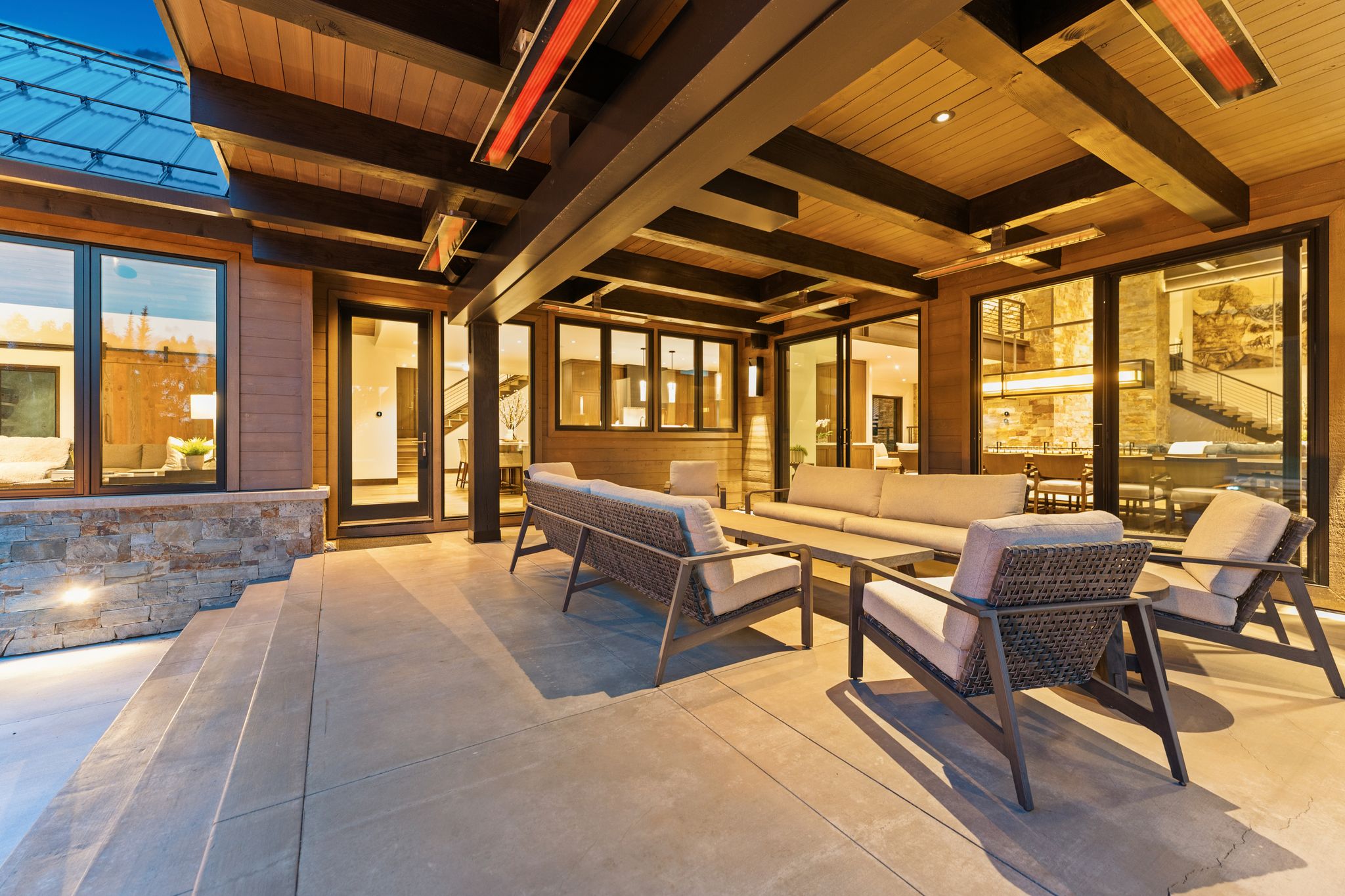 Expansive covered patio featuring a concrete surface, integrated lighting, and a wood-paneled ceiling with exposed beams
