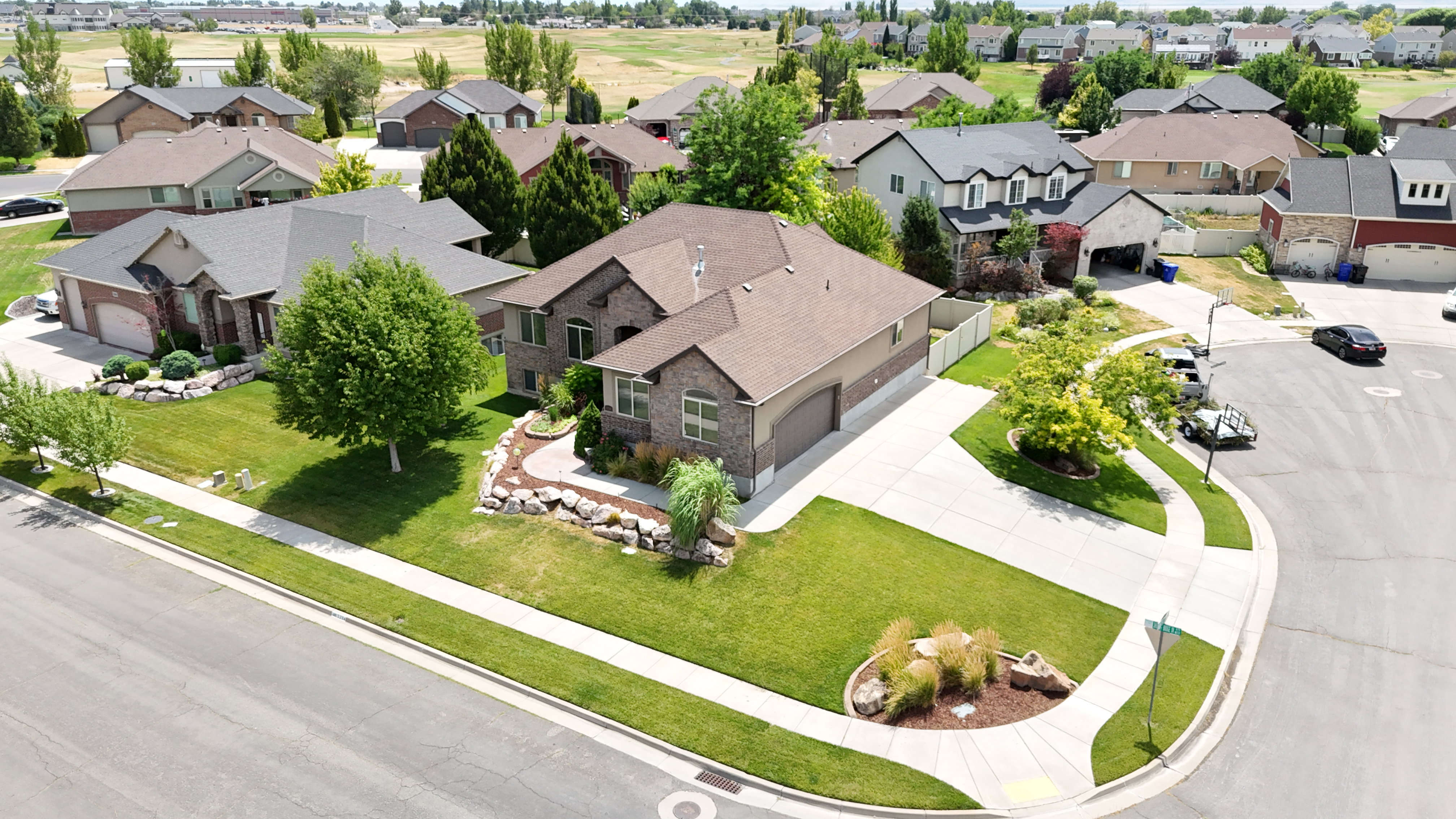 Brick exterior residence with a double garage, featuring a concrete driveway and mature landscaping