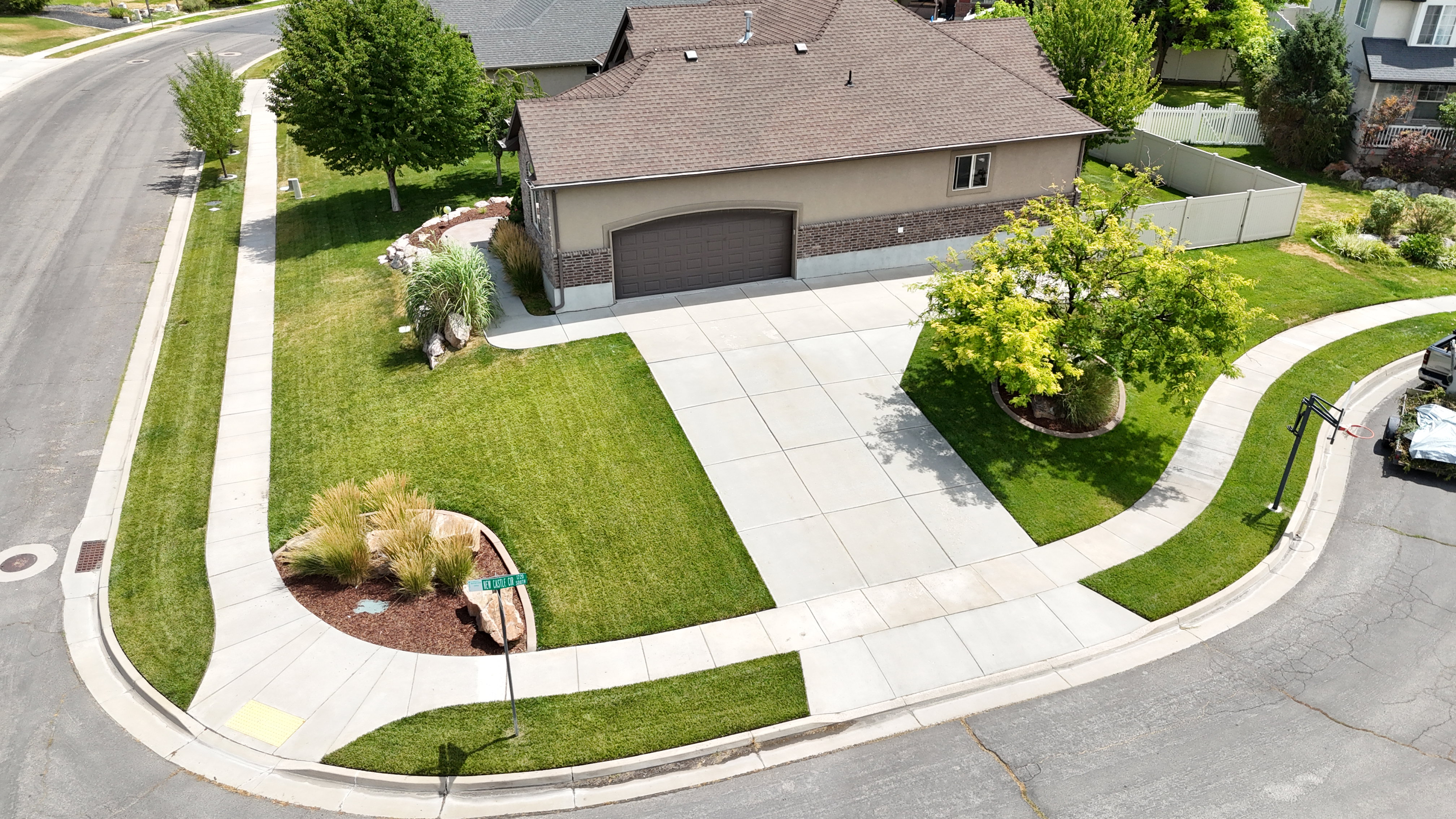 Corner lot residence featuring a two-car garage, concrete driveway, and established landscaping