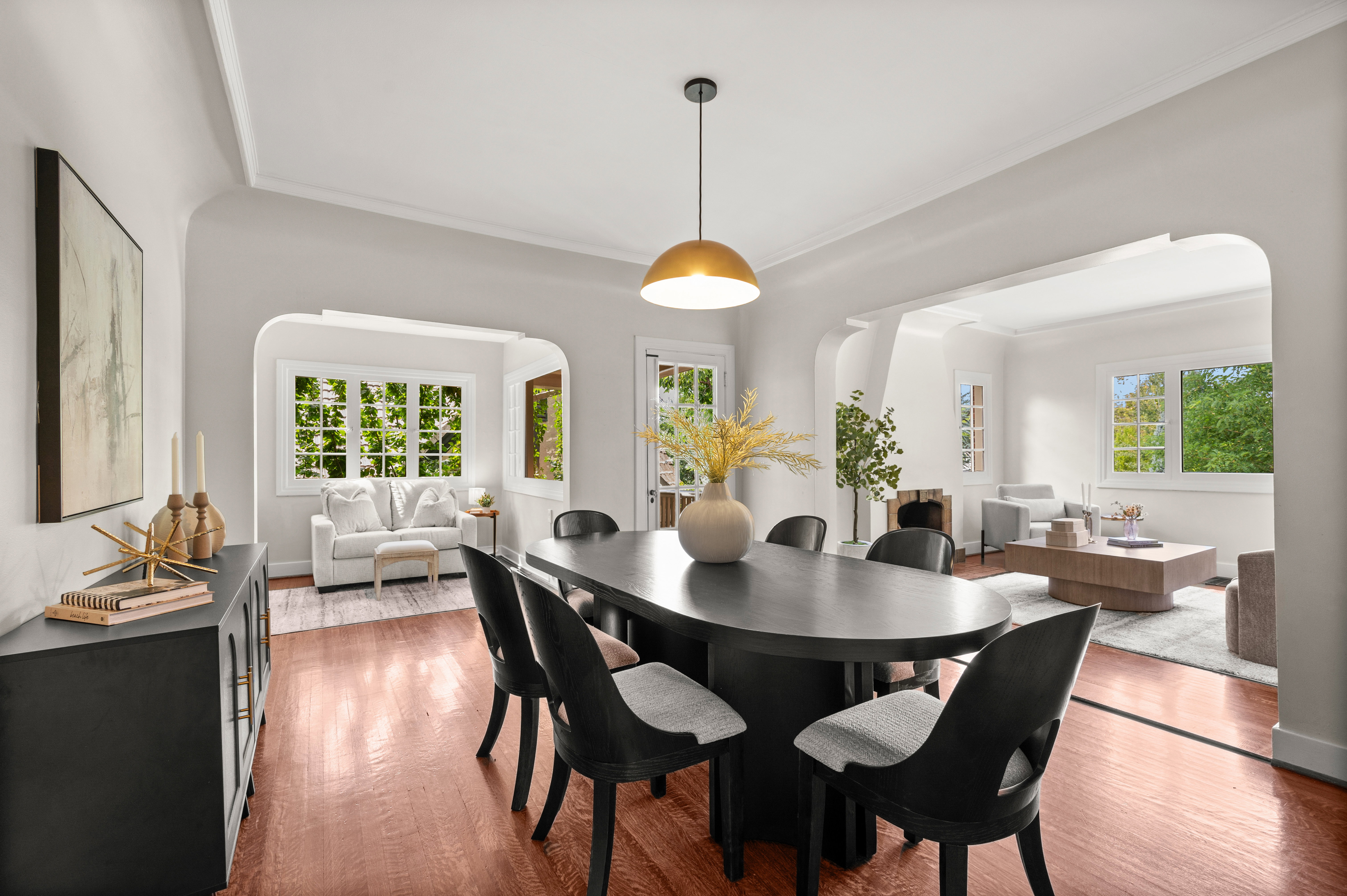 Dining area featuring wood-finish flooring, a contemporary ceiling light fixture, and arched doorways