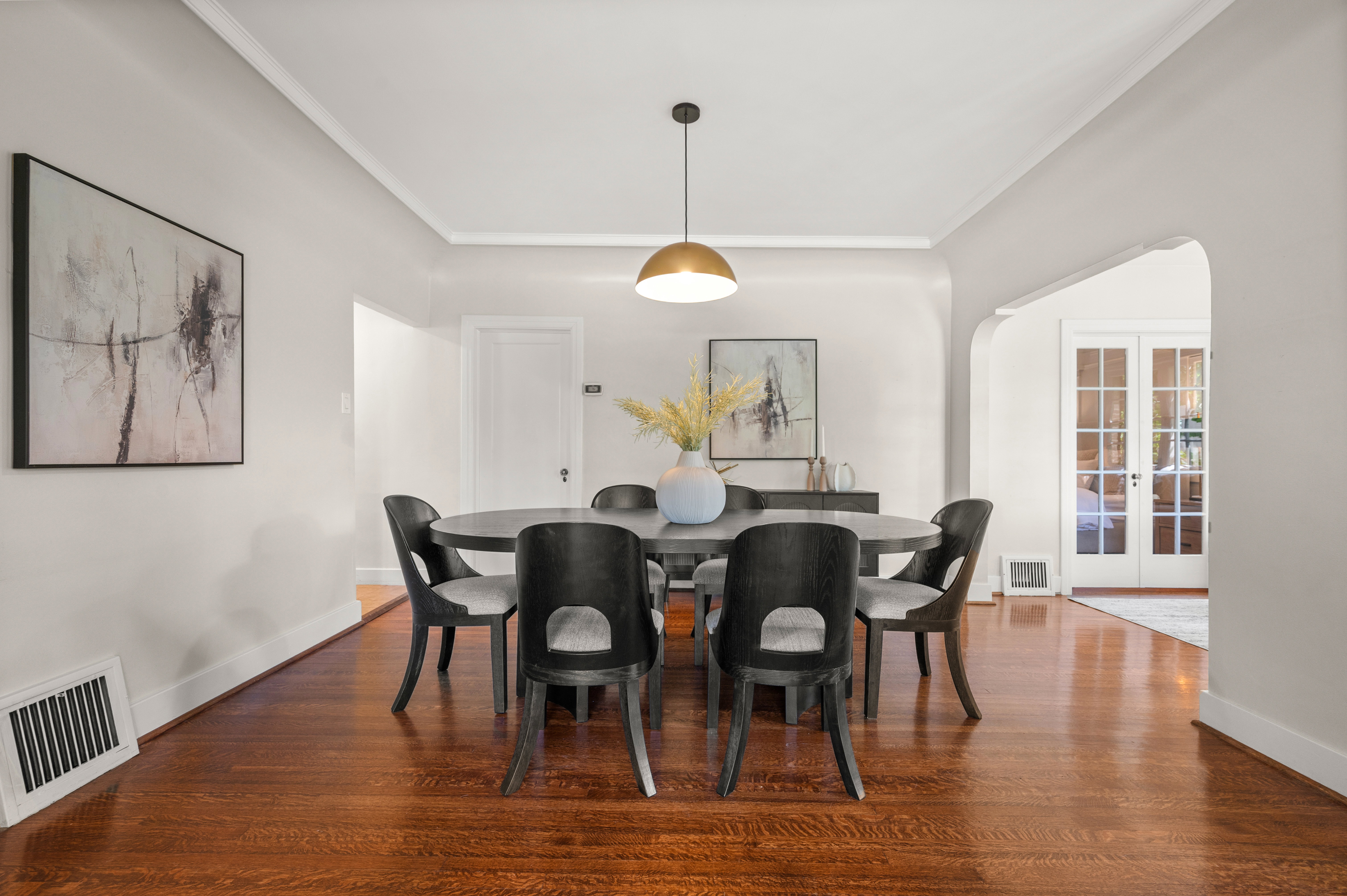 Hardwood flooring throughout, crown molding, and a brass-finish pendant light fixture