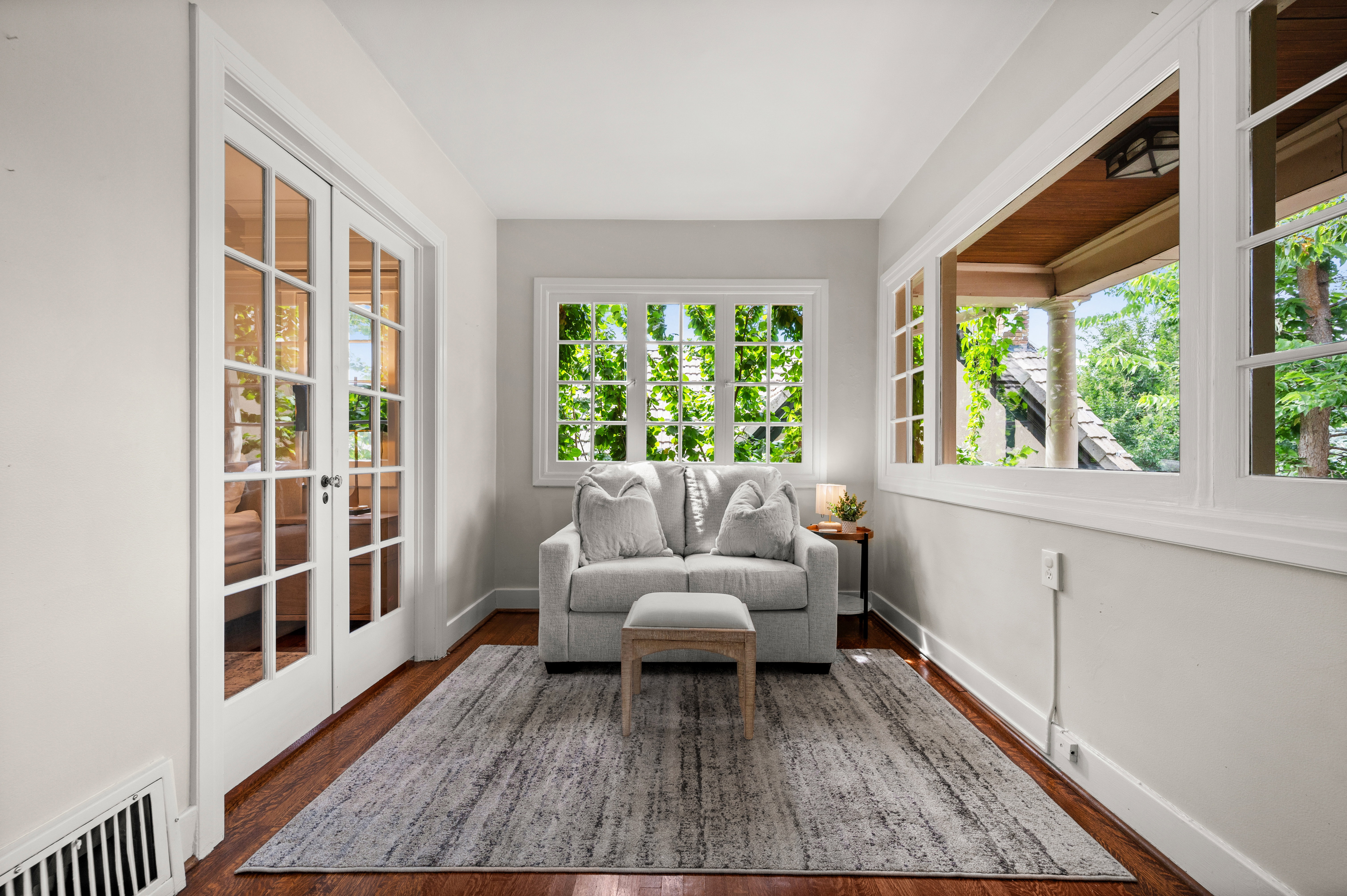 Sun-drenched room featuring rich wood-finish flooring and crisp white trim