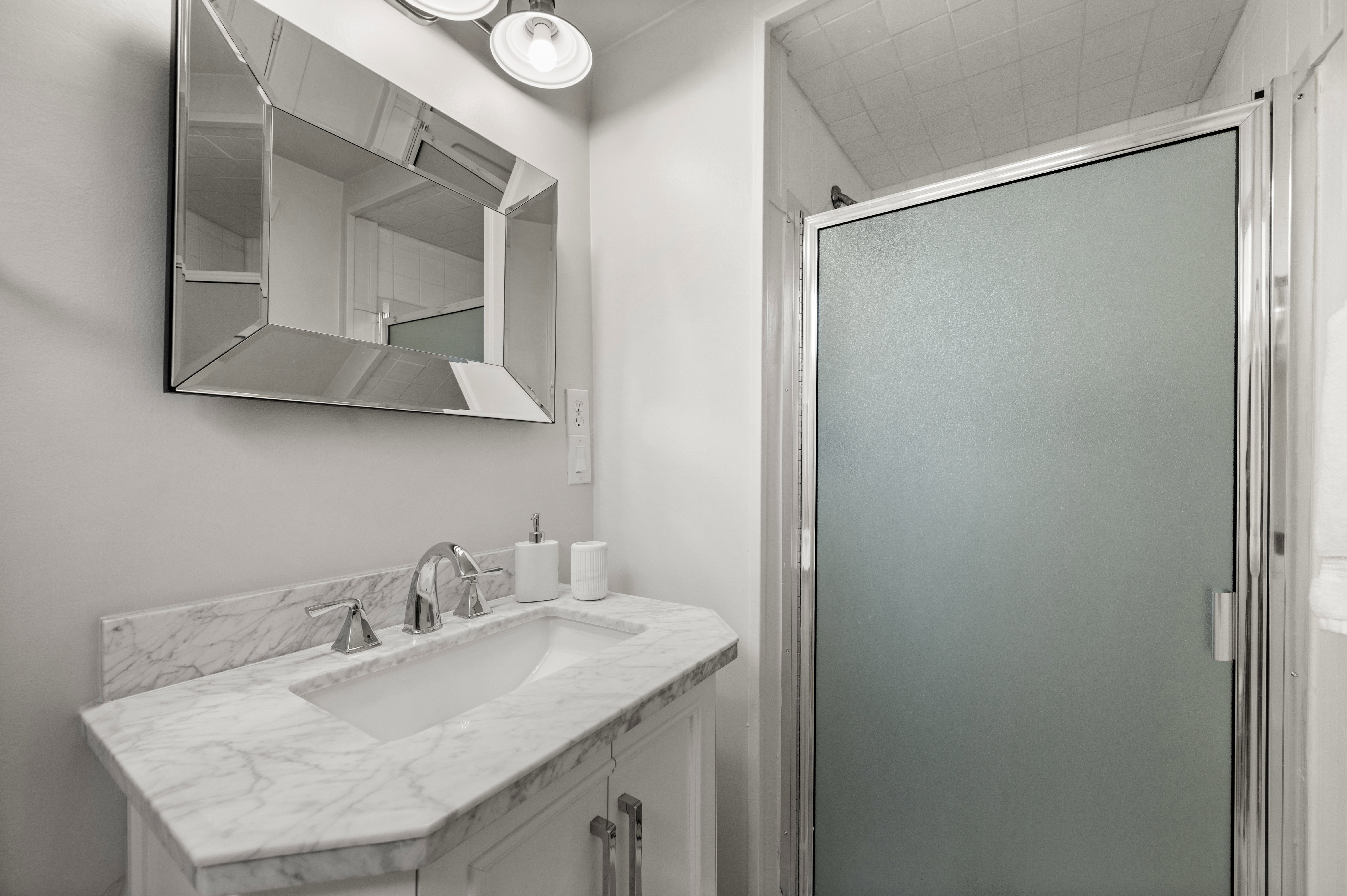Bathroom featuring a white vanity with a marble-finish countertop, undermount sink, and chrome faucet