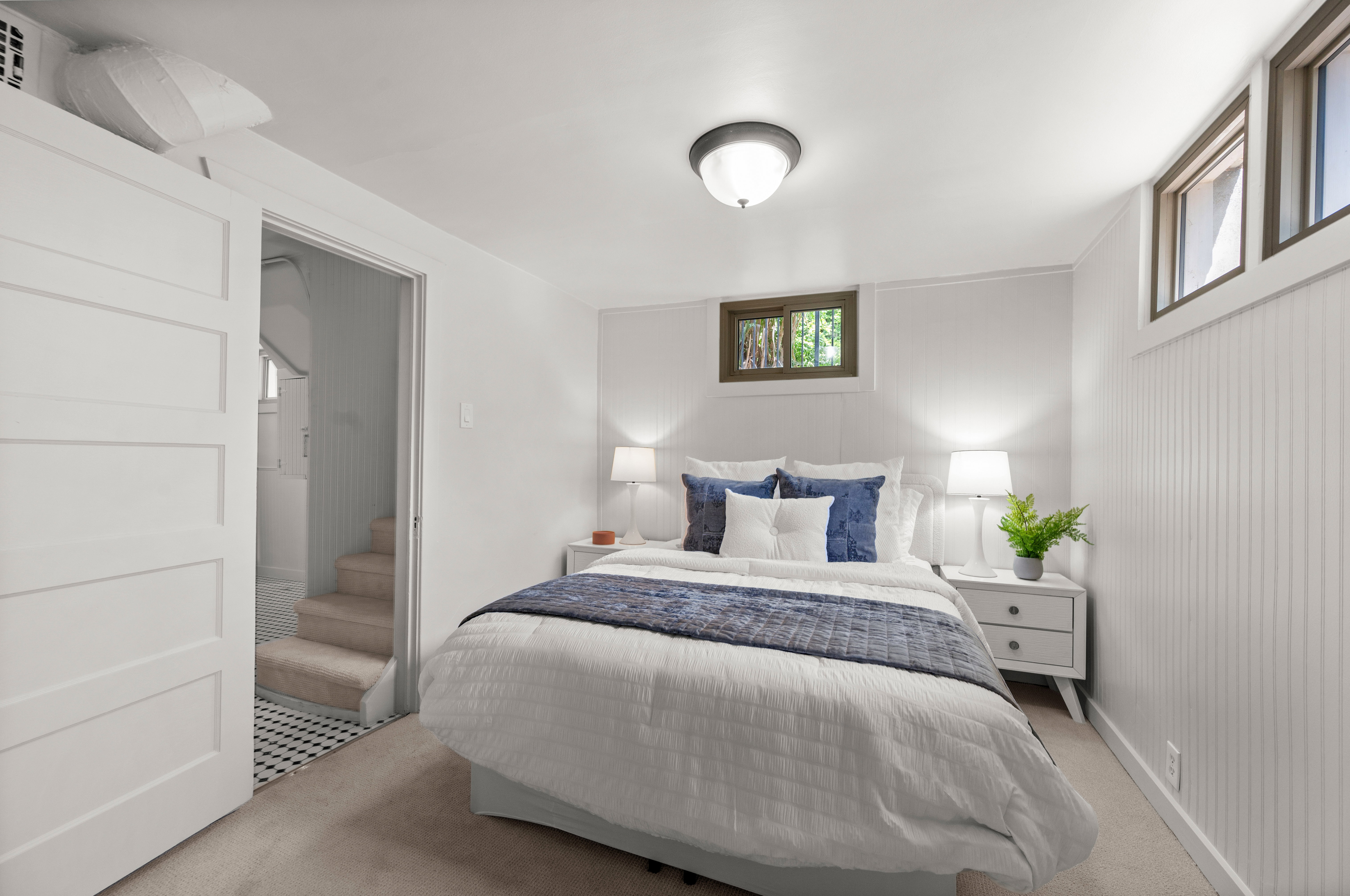 Carpeted room featuring white walls, beadboard paneling, and a white interior door