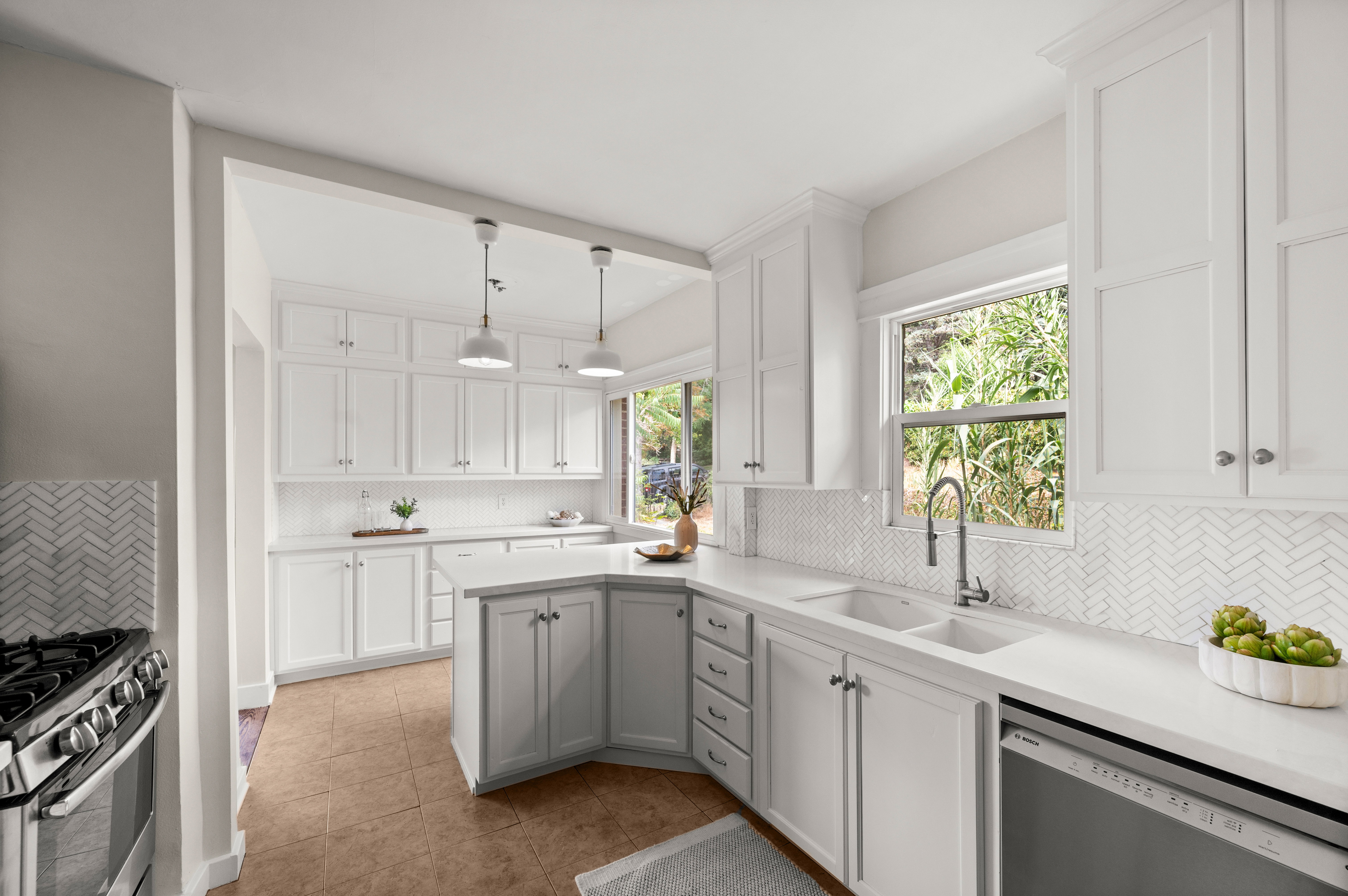 Kitchen featuring white shaker-style cabinetry, white countertops, white herringbone tile backsplash, a stainless steel gas range, and a stainless steel dishwasher