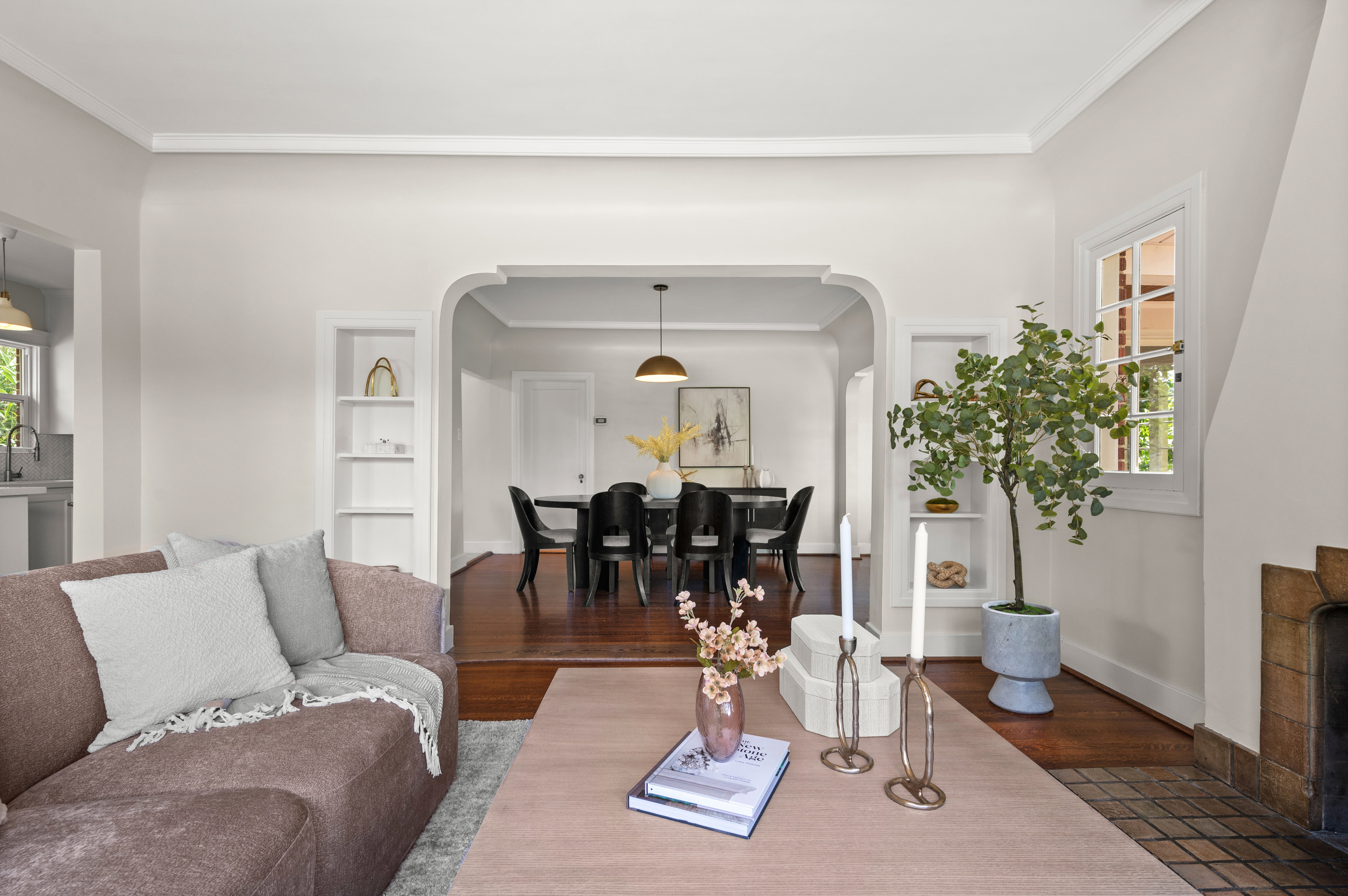 Living area featuring an arched doorway, built-in shelving, wood-finish flooring, and a window with natural light