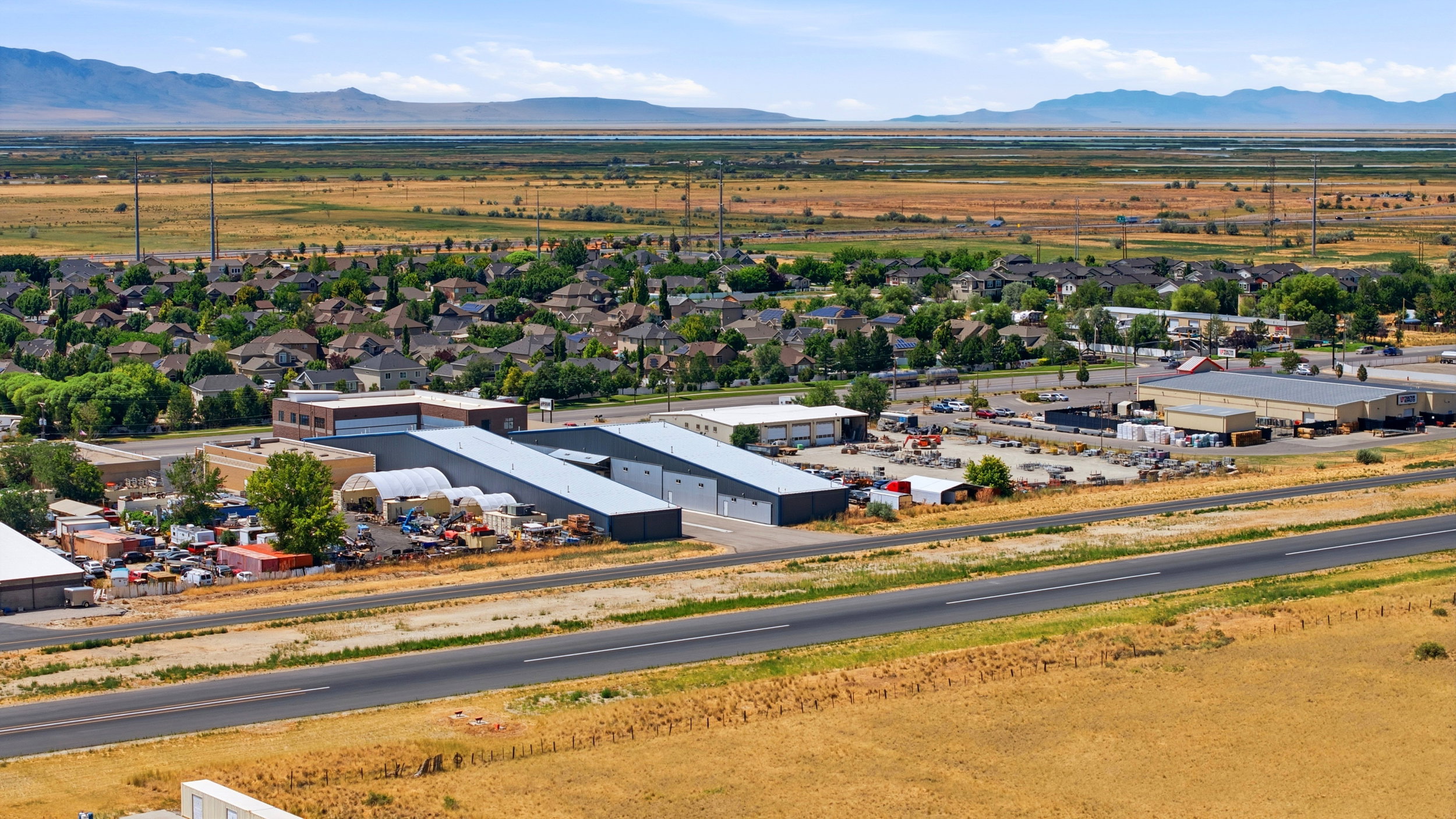 Industrial-zoned property featuring multiple large buildings with metal roofs and extensive outdoor storage areas