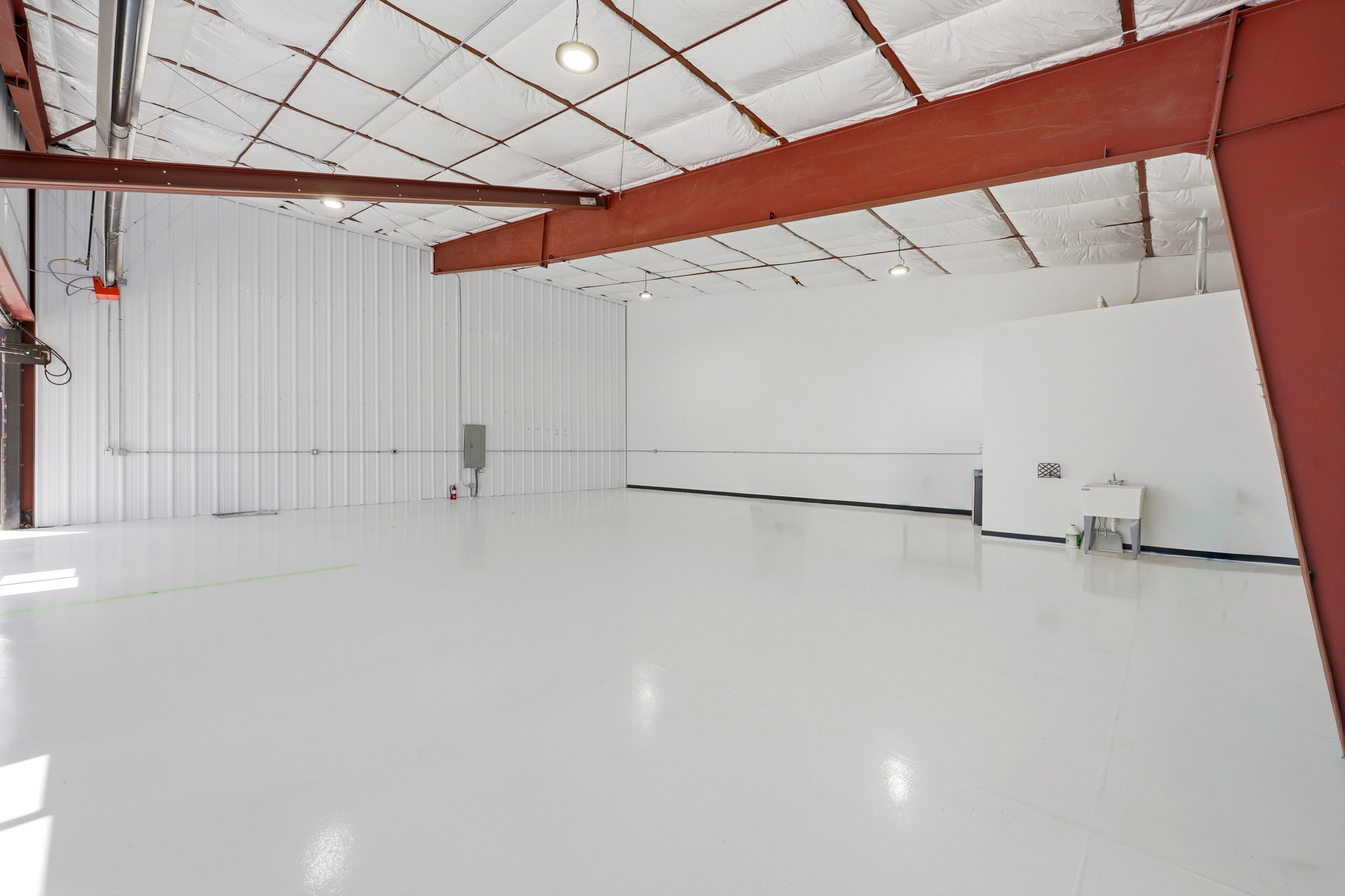 Spacious open-concept interior featuring a high, exposed truss ceiling with insulation panels and recessed lighting