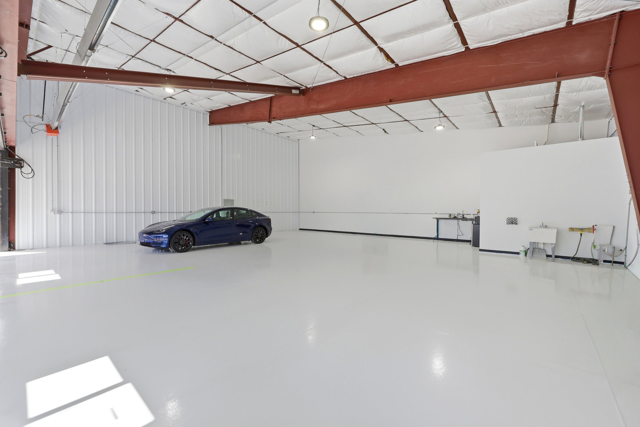 Spacious interior featuring a high ceiling, exposed steel beams, and a light-colored epoxy floor