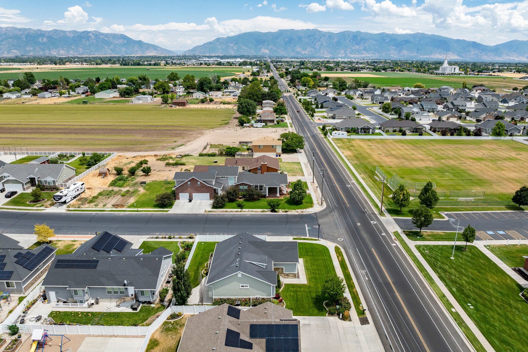 Expansive aerial view showcasing residential properties, a main thoroughfare, and a distant mountain range