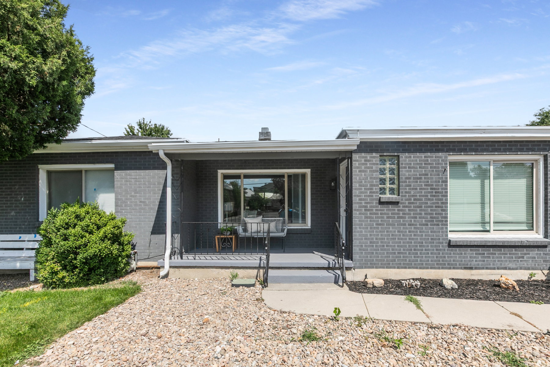Gray brick exterior featuring a covered front porch, white window trim, and a glass block window accent
