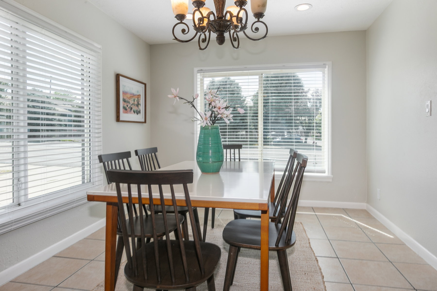 Dining area featuring tile flooring, multiple windows with blinds, a recessed ceiling light, and a decorative chandelier