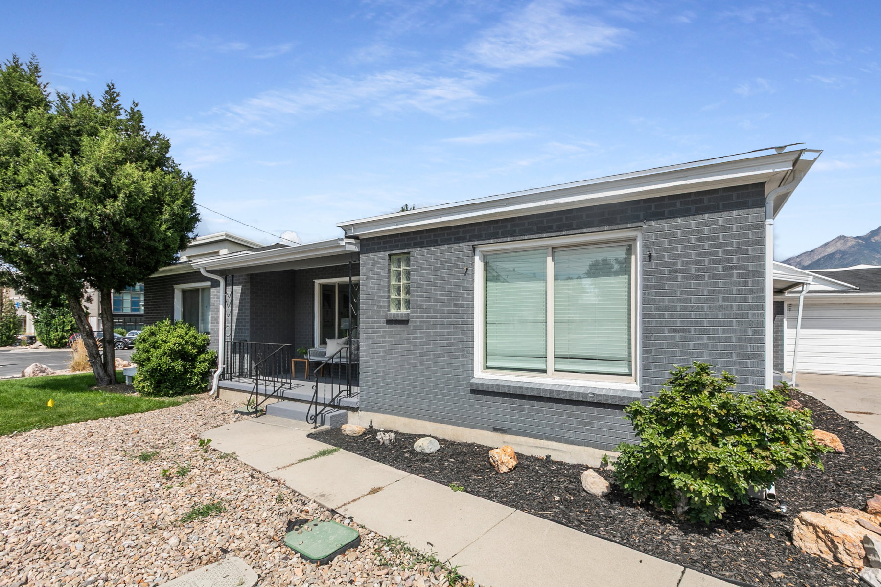 Dark gray brick exterior with white trim and a covered front porch featuring black railings