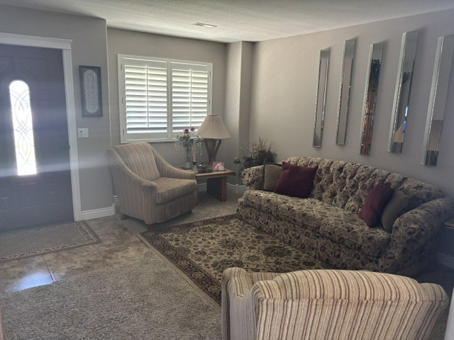Entryway featuring a dark wood door with decorative glass inserts, leading into a living area with tile flooring and carpet