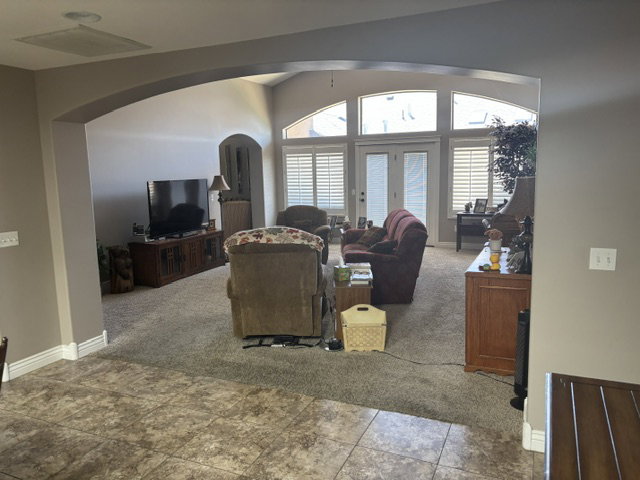 Archway entry to a carpeted living space featuring a vaulted ceiling and multiple arched transom windows