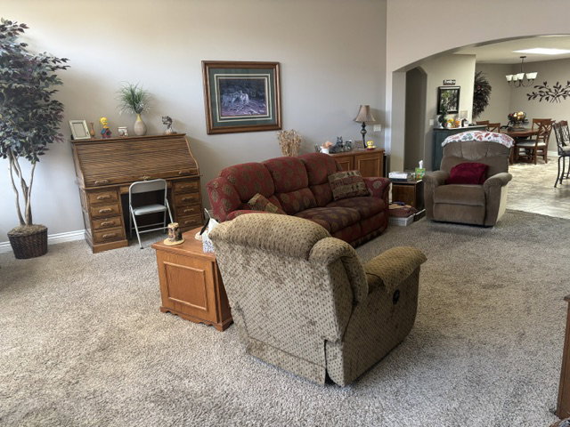 Open-concept living area with neutral-toned walls, vaulted ceilings, and plush carpeting