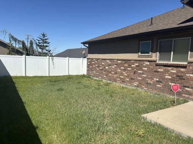 Expansive green lawn area featuring a white privacy fence