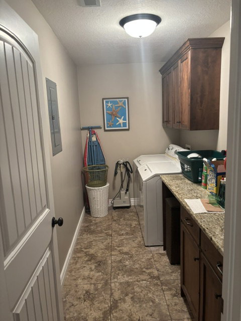 Laundry area featuring tile flooring, dark wood cabinetry, a granite-finish countertop, and a solid-core paneled door