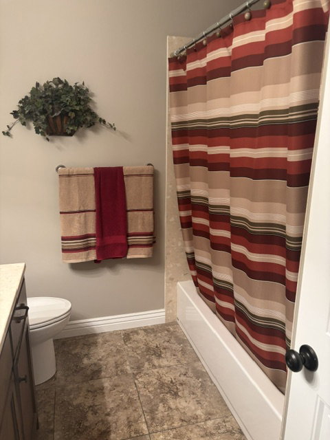 Full bathroom featuring a tub and shower combination with light-colored tile surround, a toilet, vanity with a light-toned countertop, and tile flooring