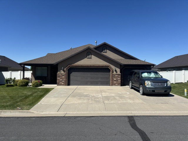 Ranch-style residence featuring a stucco exterior with brick accents, a two-car garage, and a covered entry