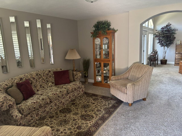 Open living area featuring neutral wall tones, arched entryway, and light-toned carpeting