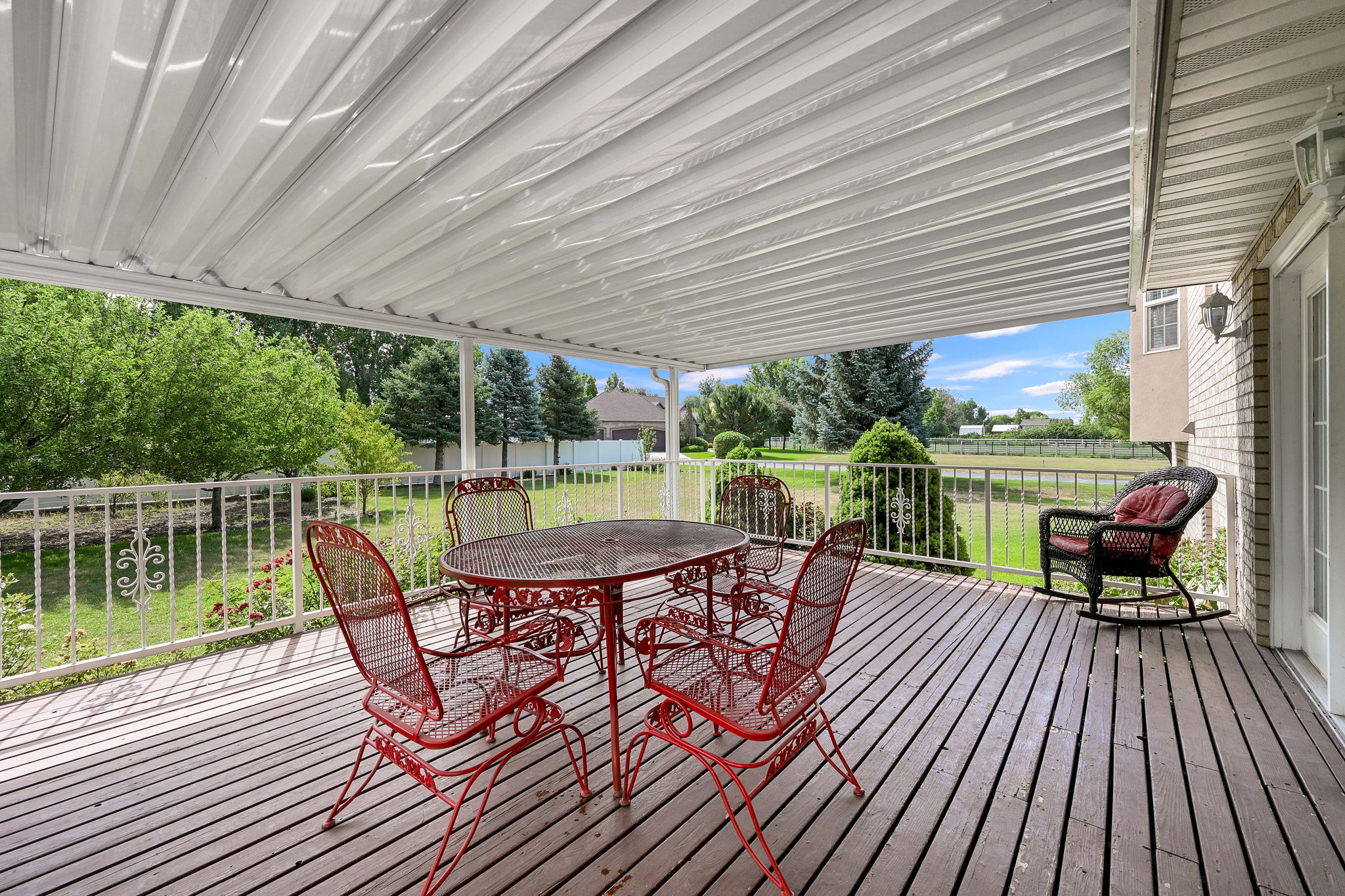 Covered outdoor deck featuring wood flooring and decorative white railings