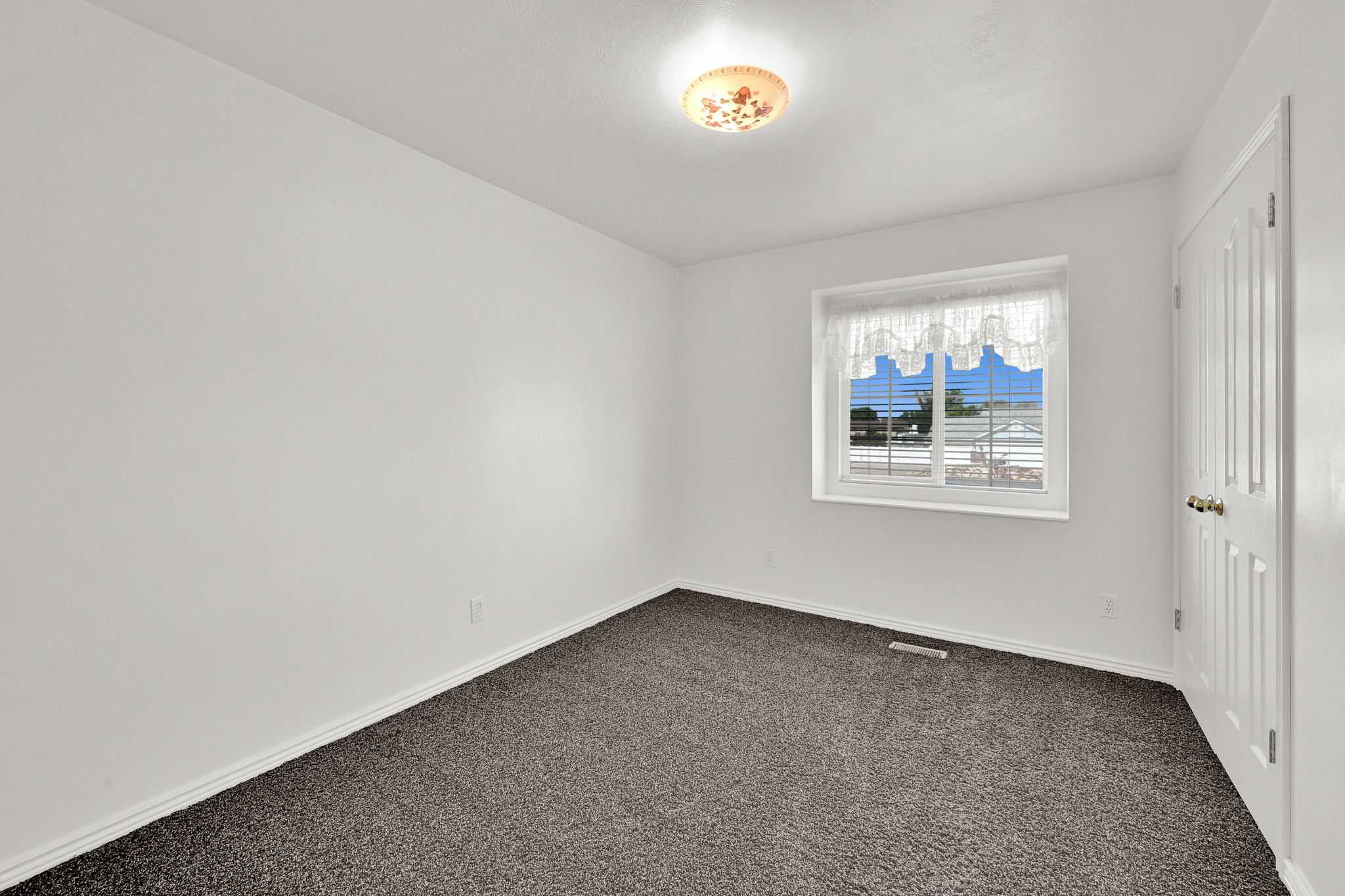 Room featuring light gray textured carpeting, white walls, and a white ceiling with a flush-mount light fixture