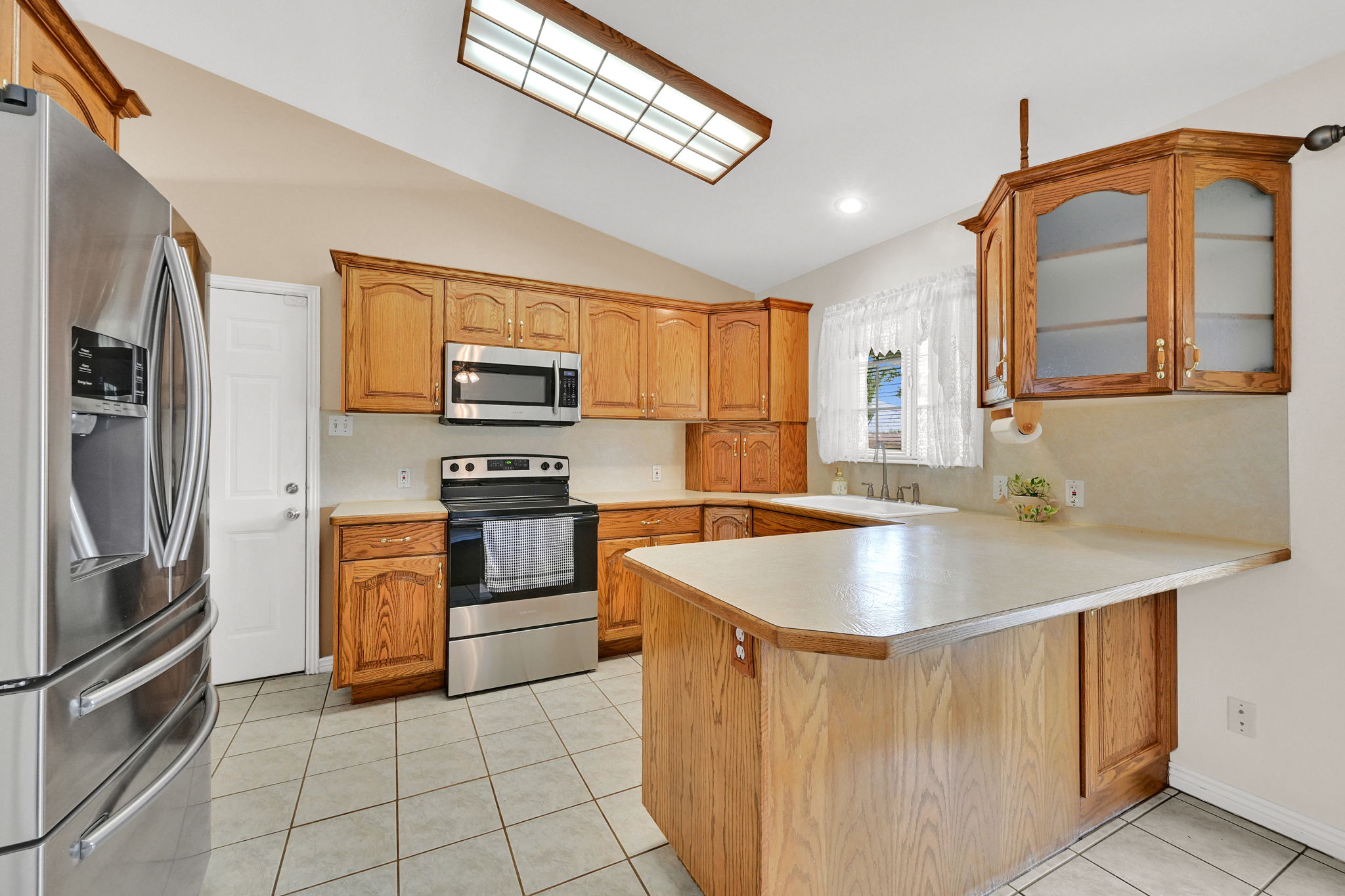 Kitchen featuring wood cabinetry, stainless steel appliances, a breakfast bar, recessed lighting, and tile flooring