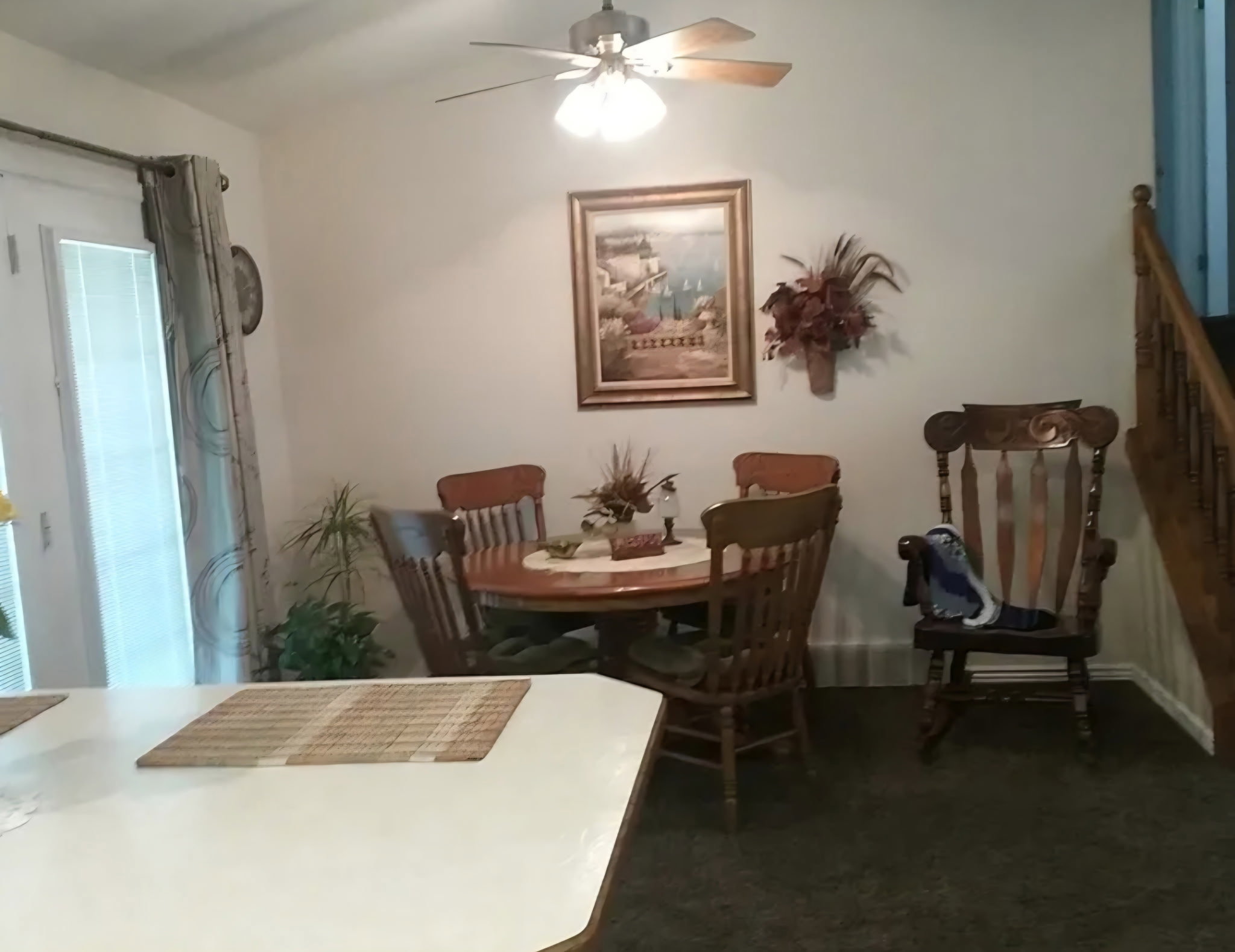 Dining area featuring a ceiling fan with integrated lighting, a glass-paneled door, and wood-finish stair railing