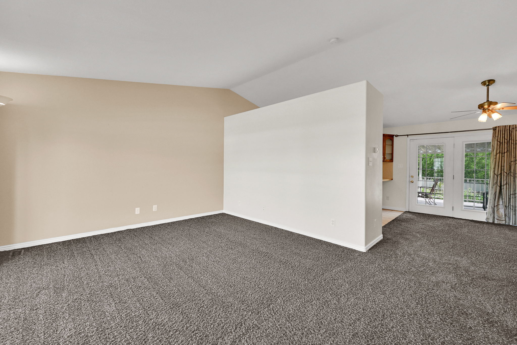 Spacious interior featuring neutral carpeting, vaulted ceilings, and a partial dividing wall