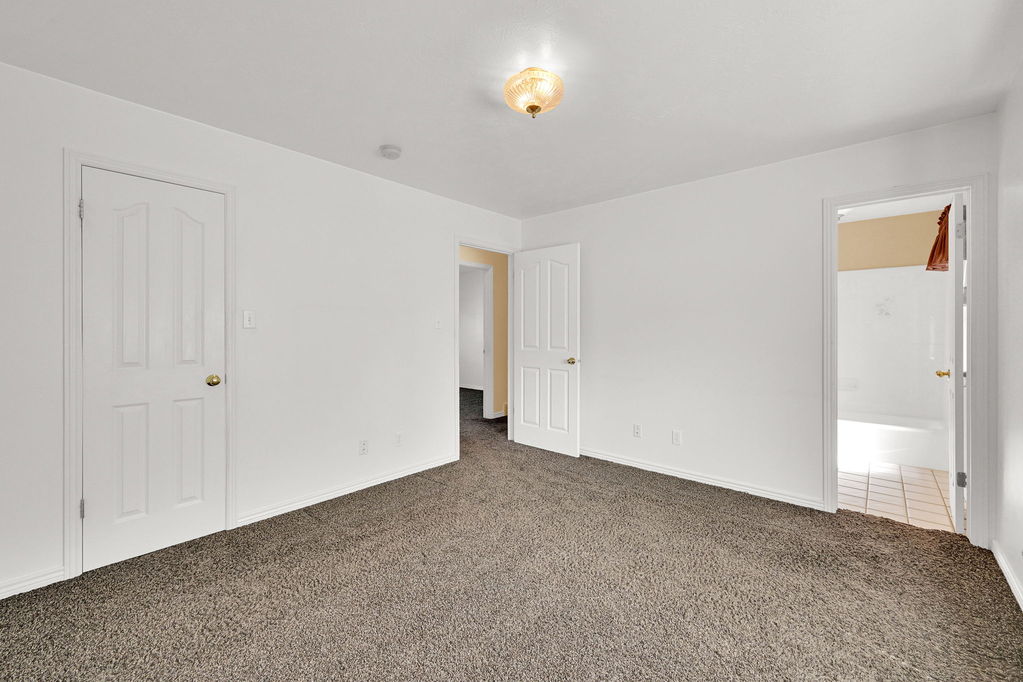 Carpeted room featuring white walls and a ceiling-mounted light fixture