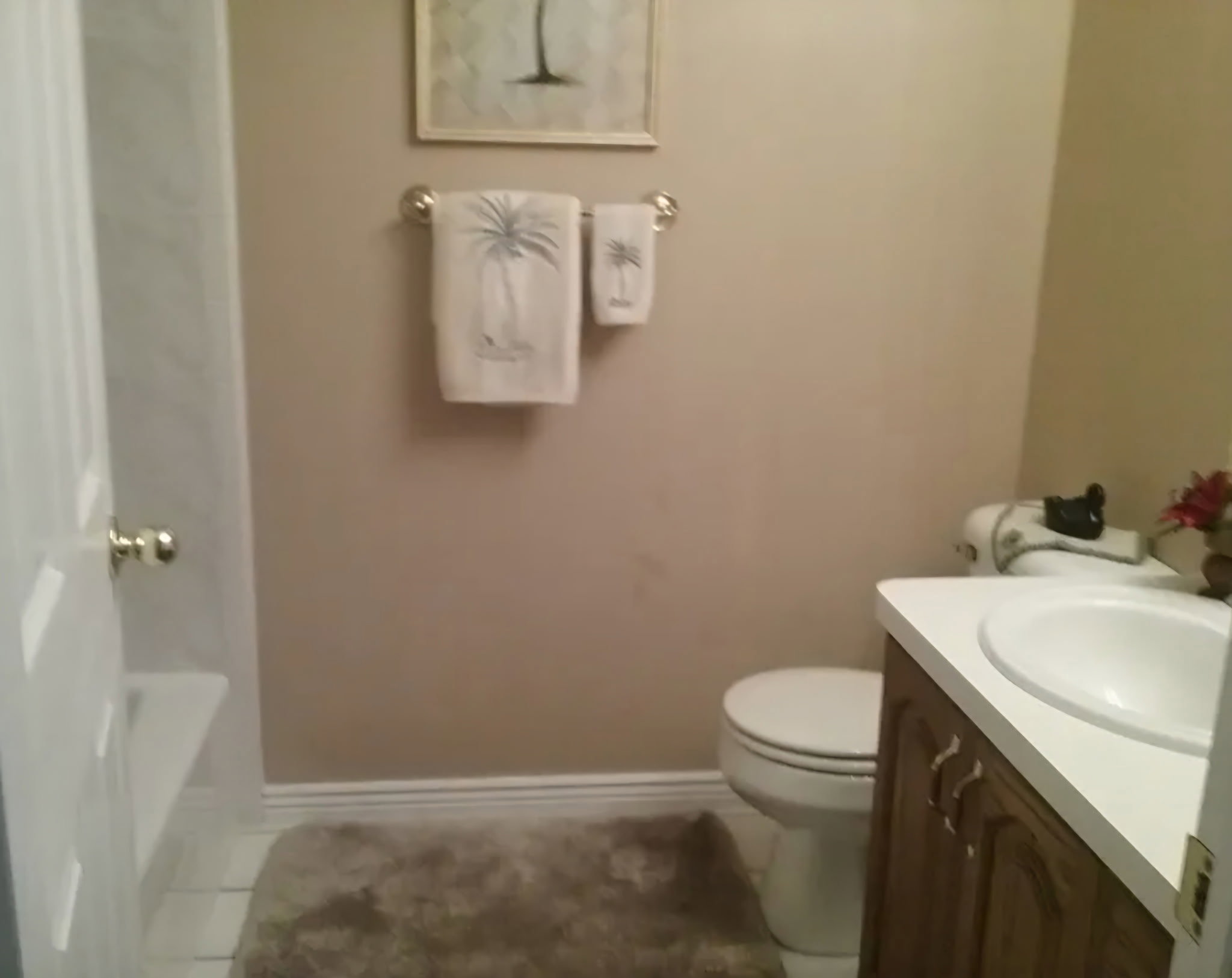 Bathroom featuring a white bathtub, wood-finish vanity with a white countertop and integrated sink, and white baseboards