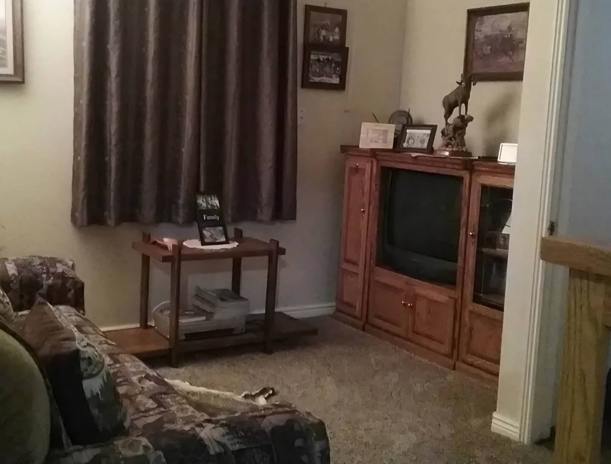 Carpeted interior space featuring a window with drapes, a built-in entertainment center, and neutral wall tones