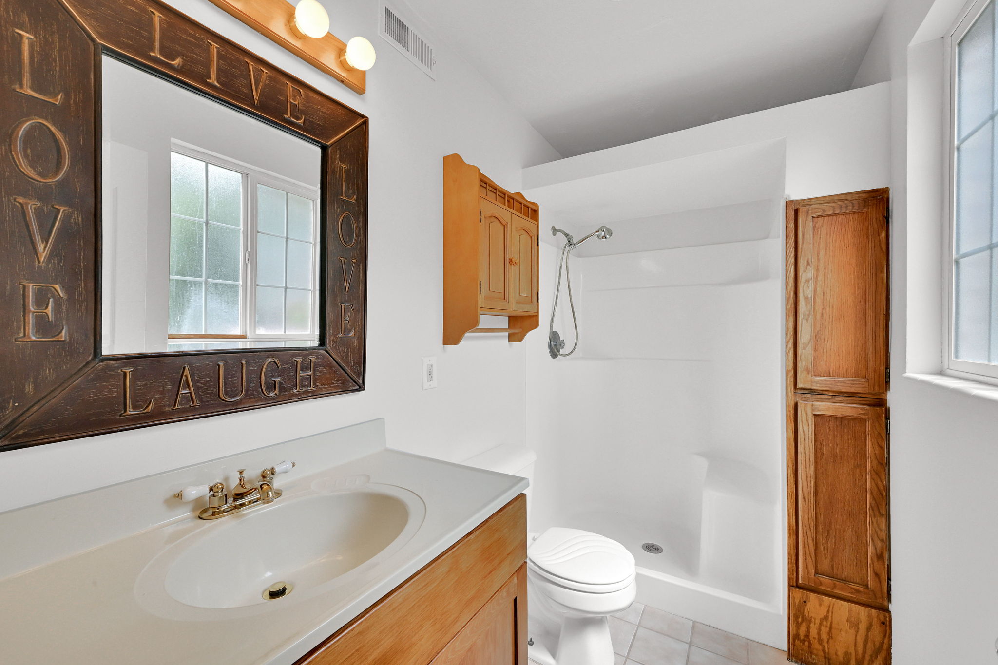 Bathroom featuring a vanity with an integrated sink, a built-in shower, tiled flooring, and a window with privacy glass