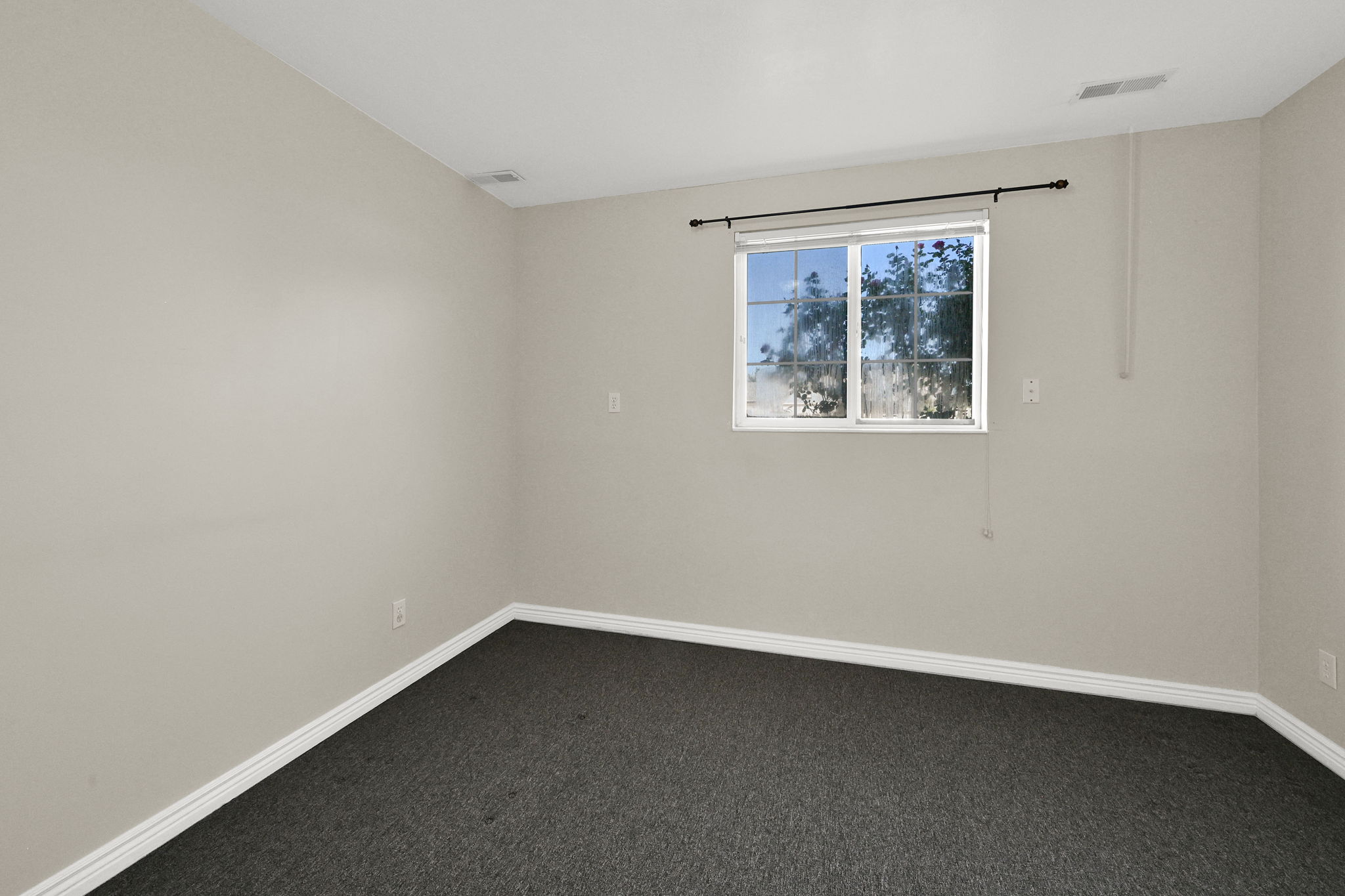 Interior space featuring neutral wall paint, dark carpeting, and white baseboards