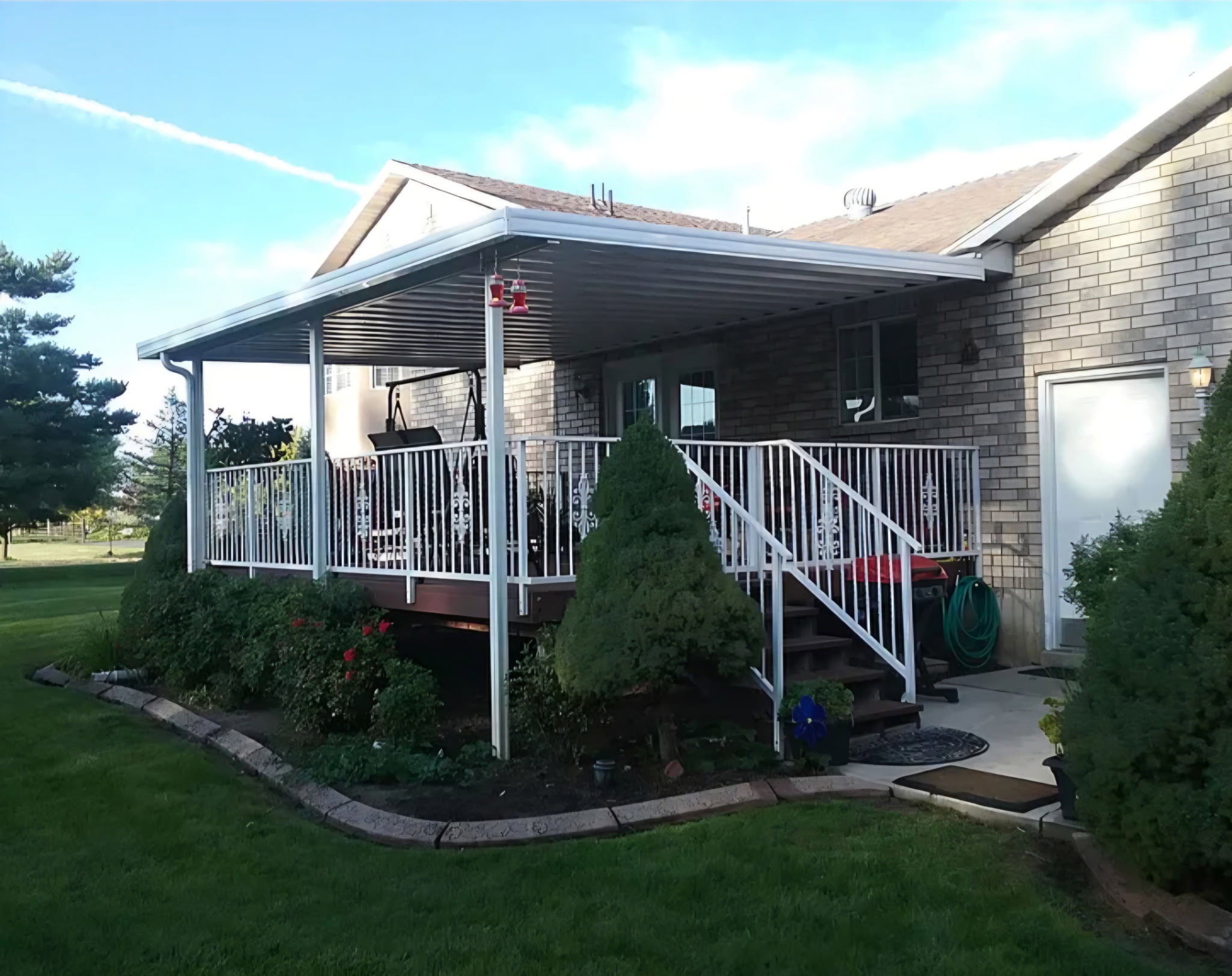 Spacious outdoor deck featuring a white railing system, dark wood-finish decking, and a full-coverage patio awning