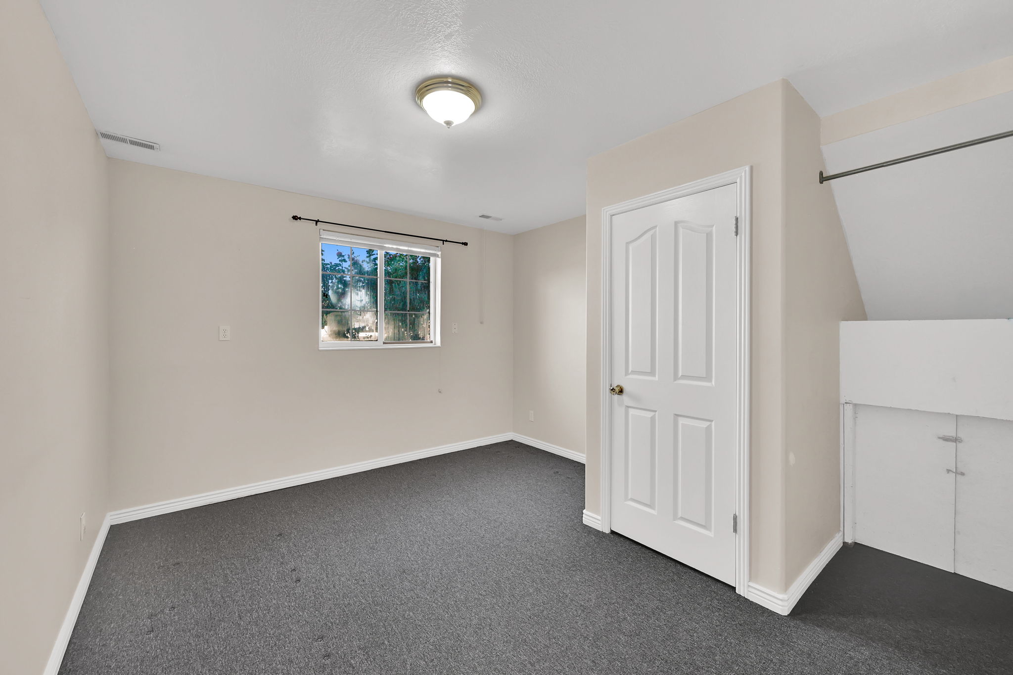 Carpeted room featuring a double-pane window, neutral-toned walls, white trim, and a six-panel interior door