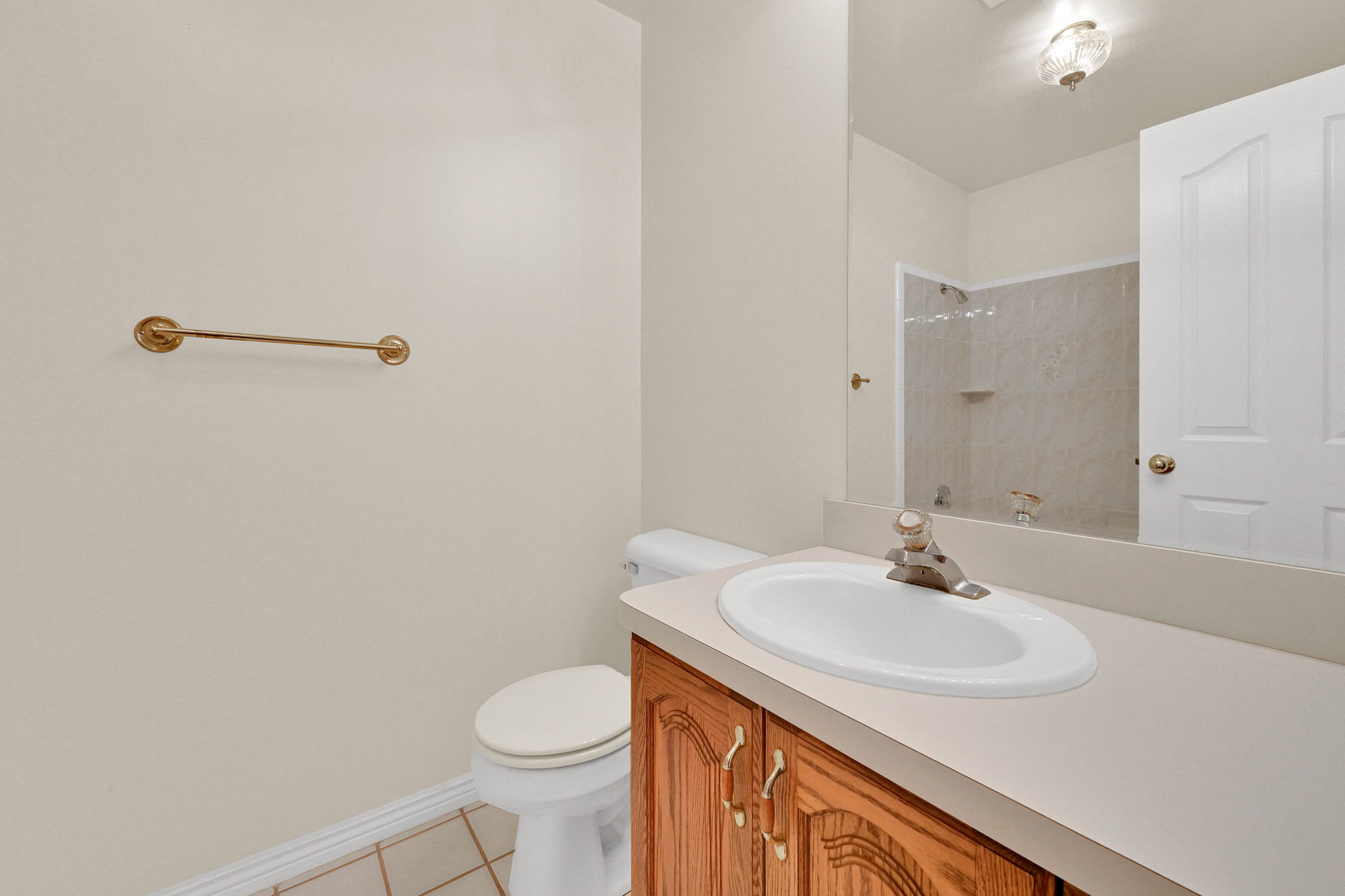Bathroom featuring a wood-finish vanity with a light-toned countertop, an oval undermount sink, and a large wall-mounted mirror