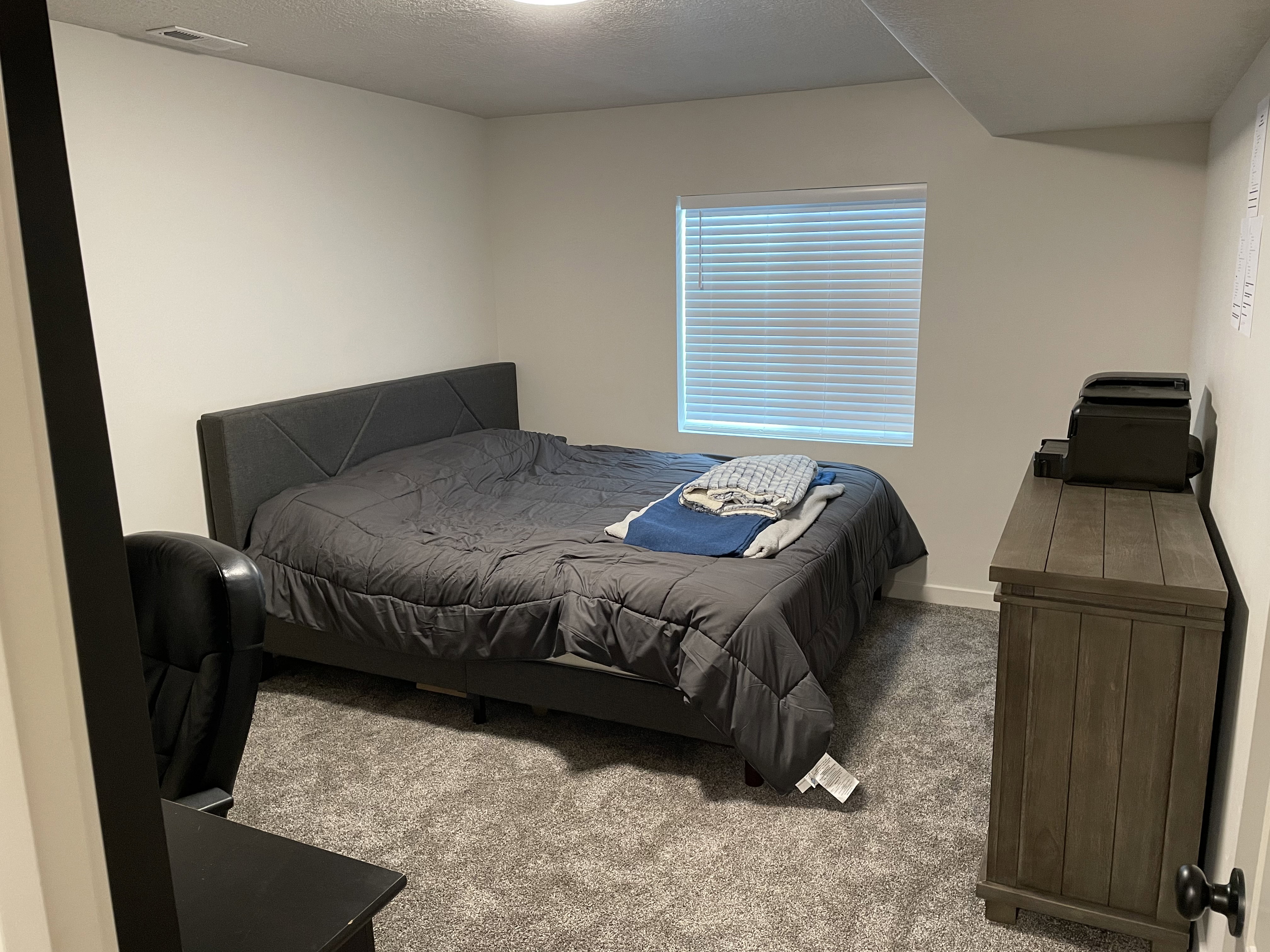 Carpeted room with a window featuring horizontal blinds