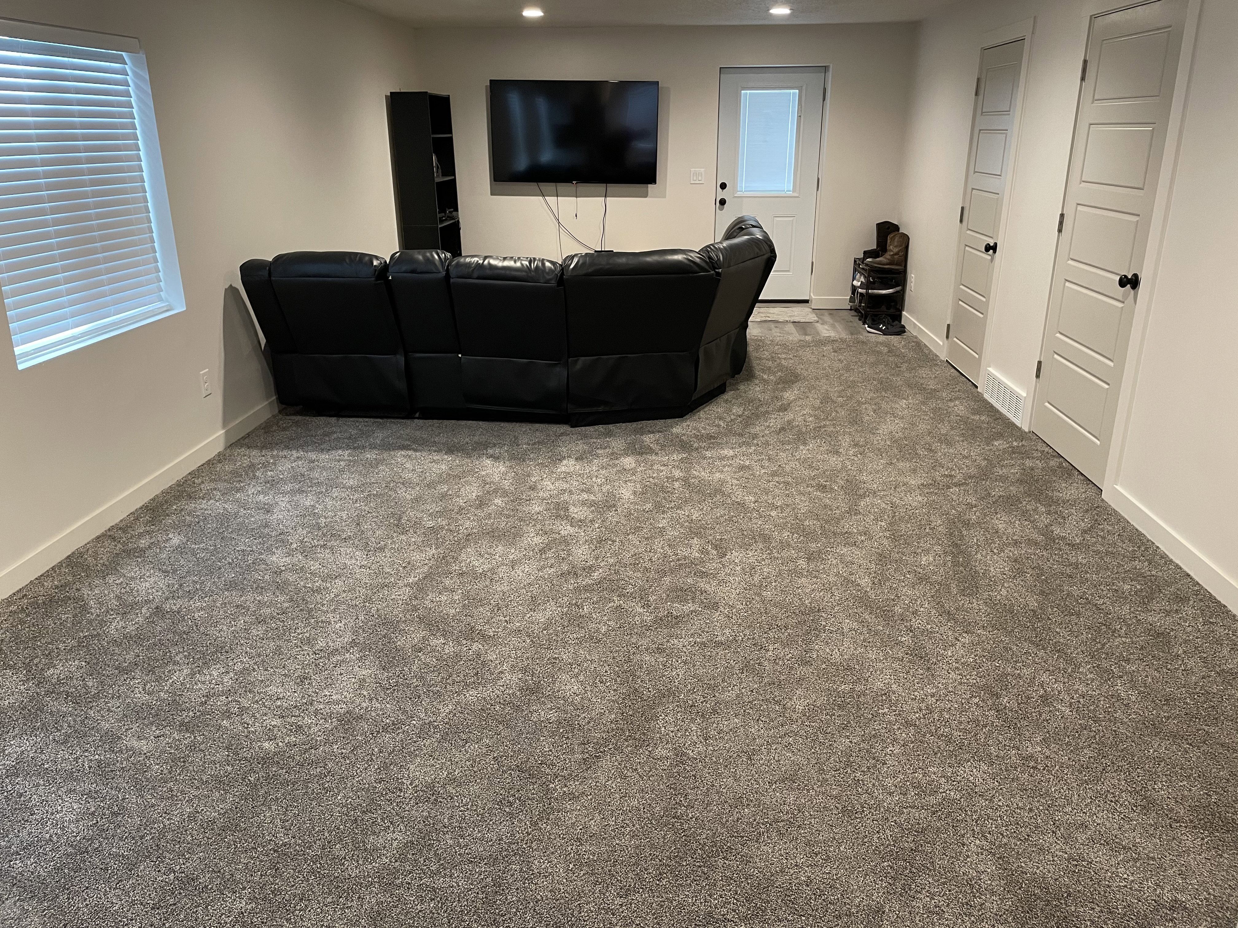 Spacious carpeted room featuring white trim, a window with blinds, and recessed lighting