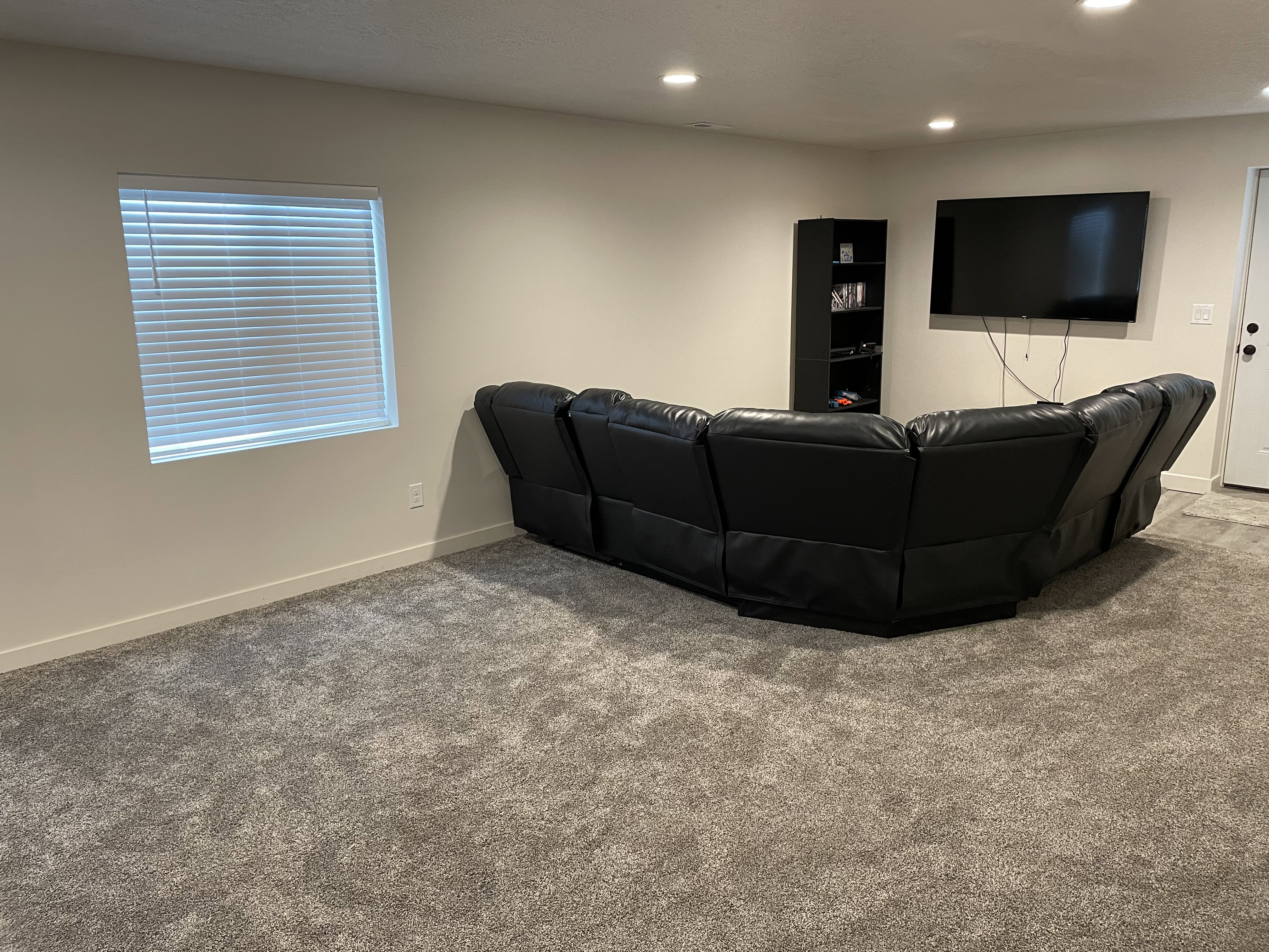 Spacious living area featuring neutral-toned walls, recessed lighting, and grey carpeting
