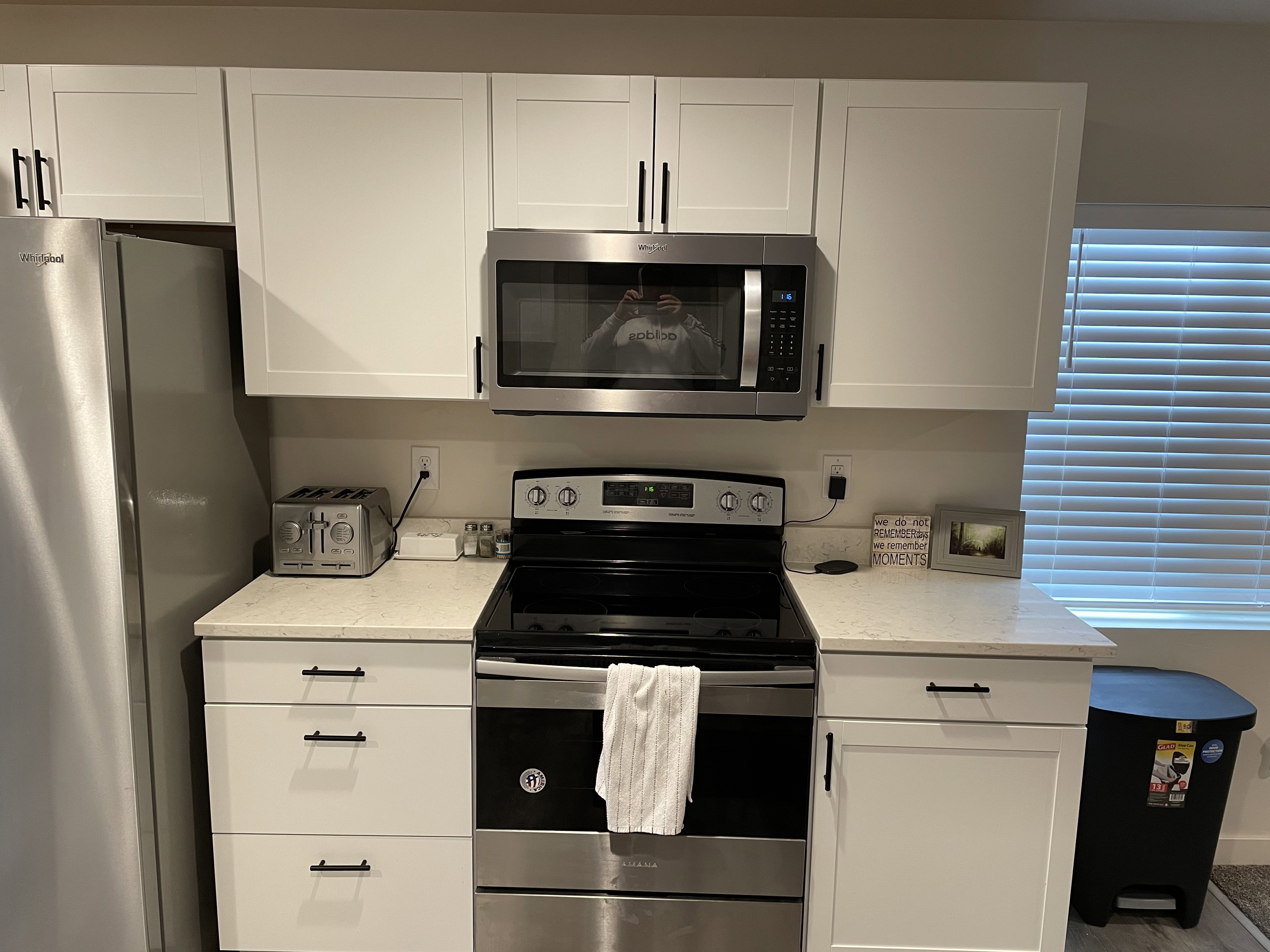 Modern kitchen featuring stainless steel appliances, white shaker-style cabinetry, and light-colored countertops