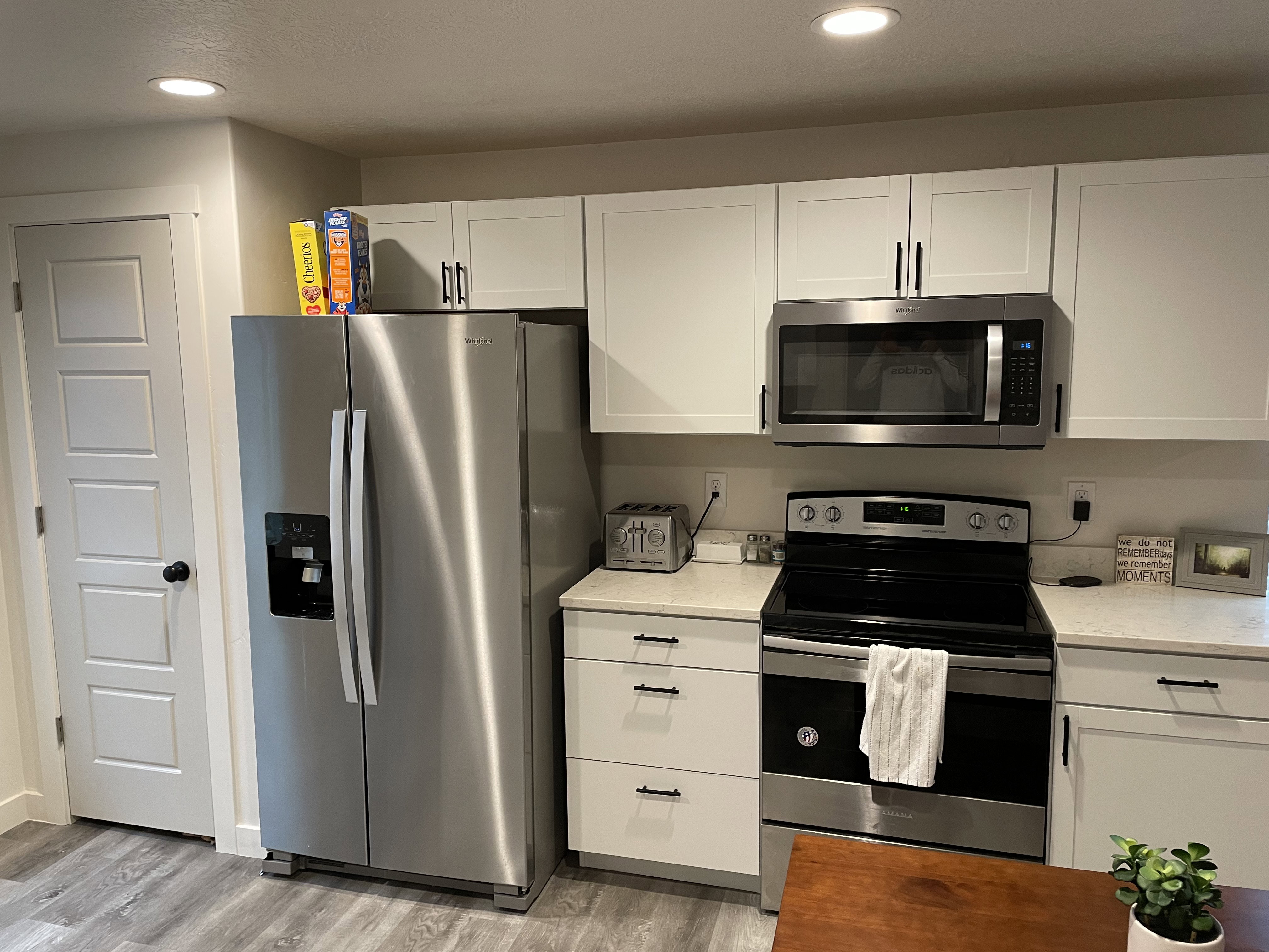 Kitchen featuring white shaker-style cabinetry, light-toned countertops, and wood-finish flooring