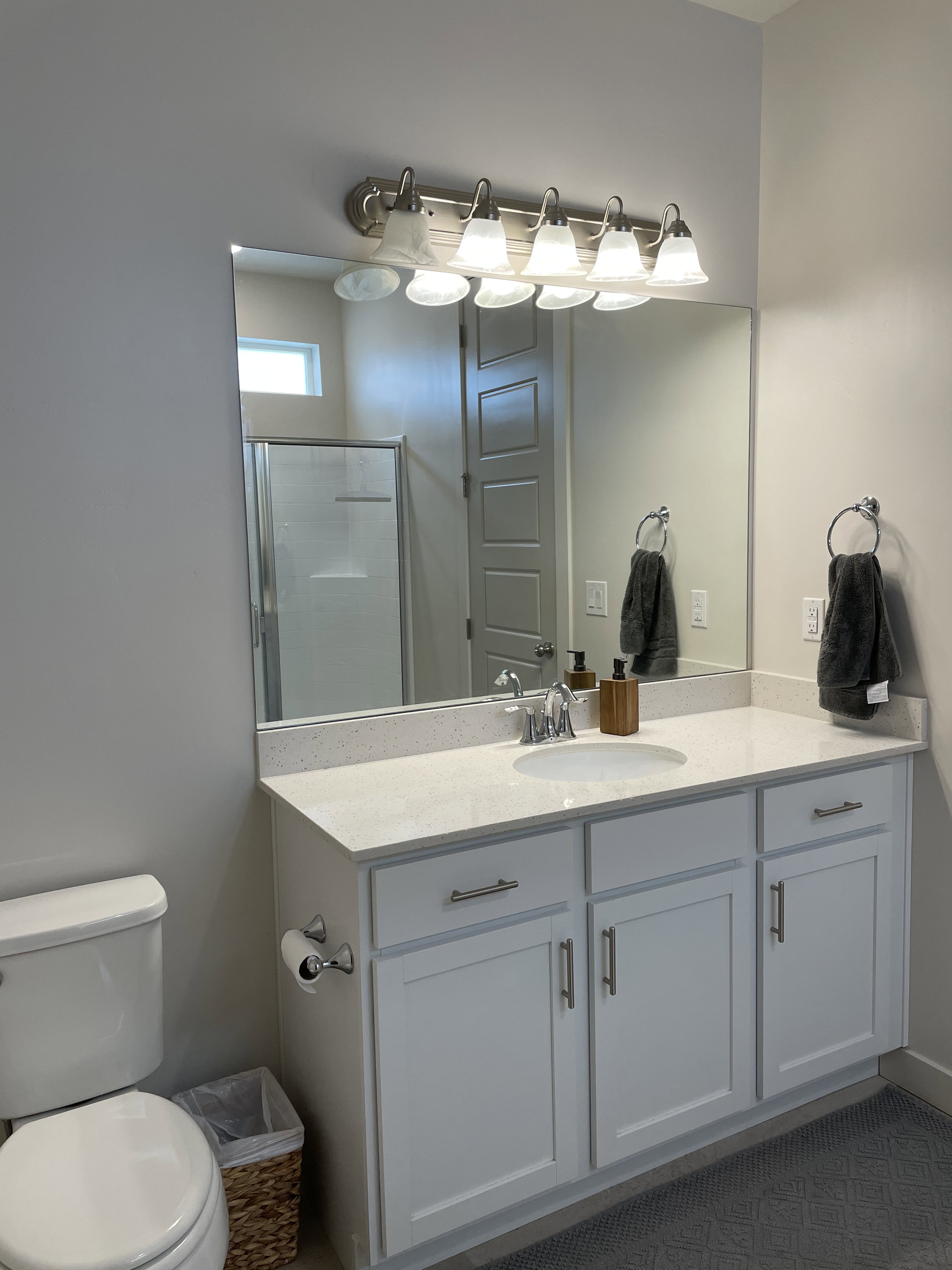 Bathroom vanity featuring a single basin, stainless steel faucet, and a light-toned countertop