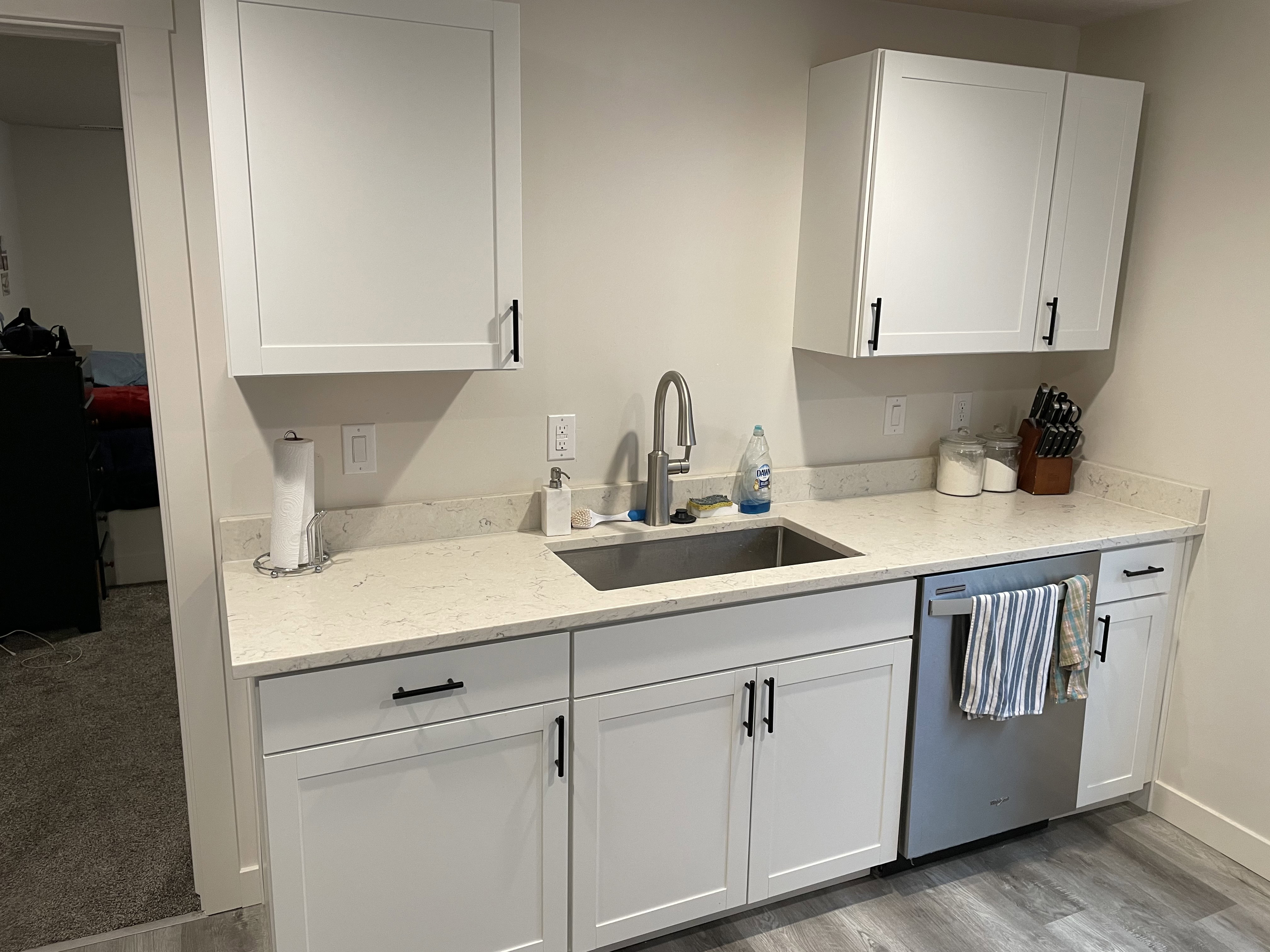 Bright white shaker cabinetry with matte black hardware, a stainless steel sink, and a high-arc faucet